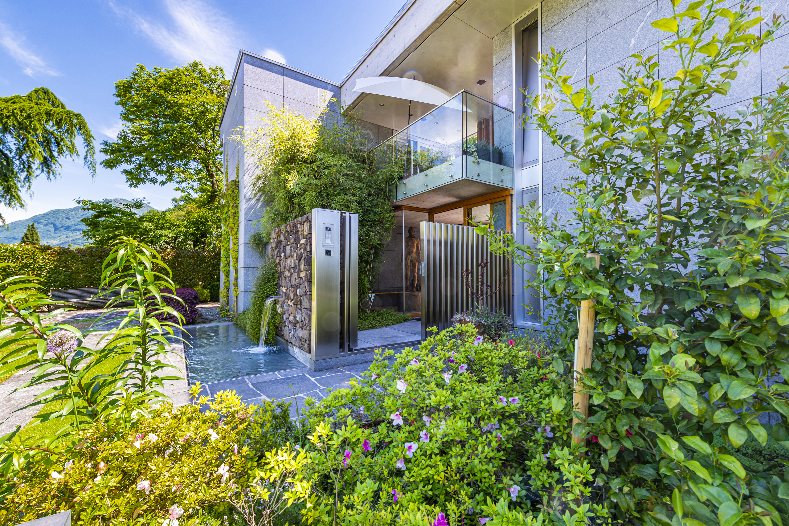 Moderne Villenfassade mit Garten und Wasserbecken