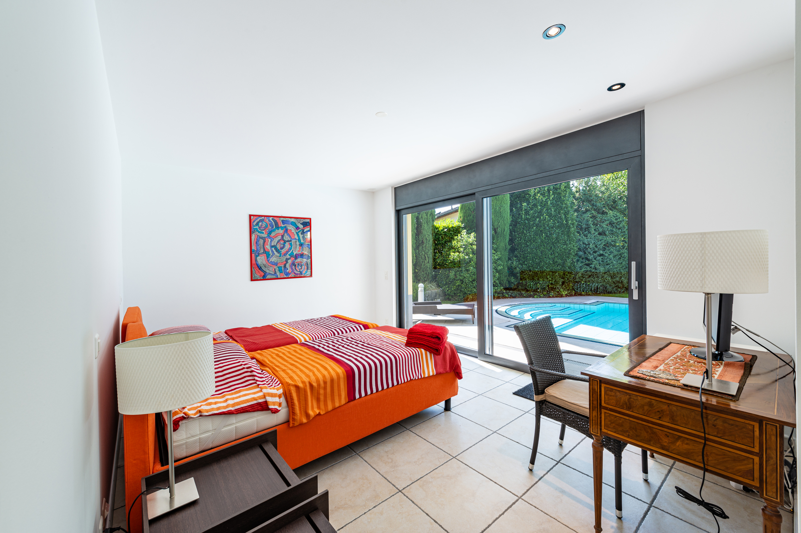 Helles Schlafzimmer mit Terrassenzugang und Poolblick