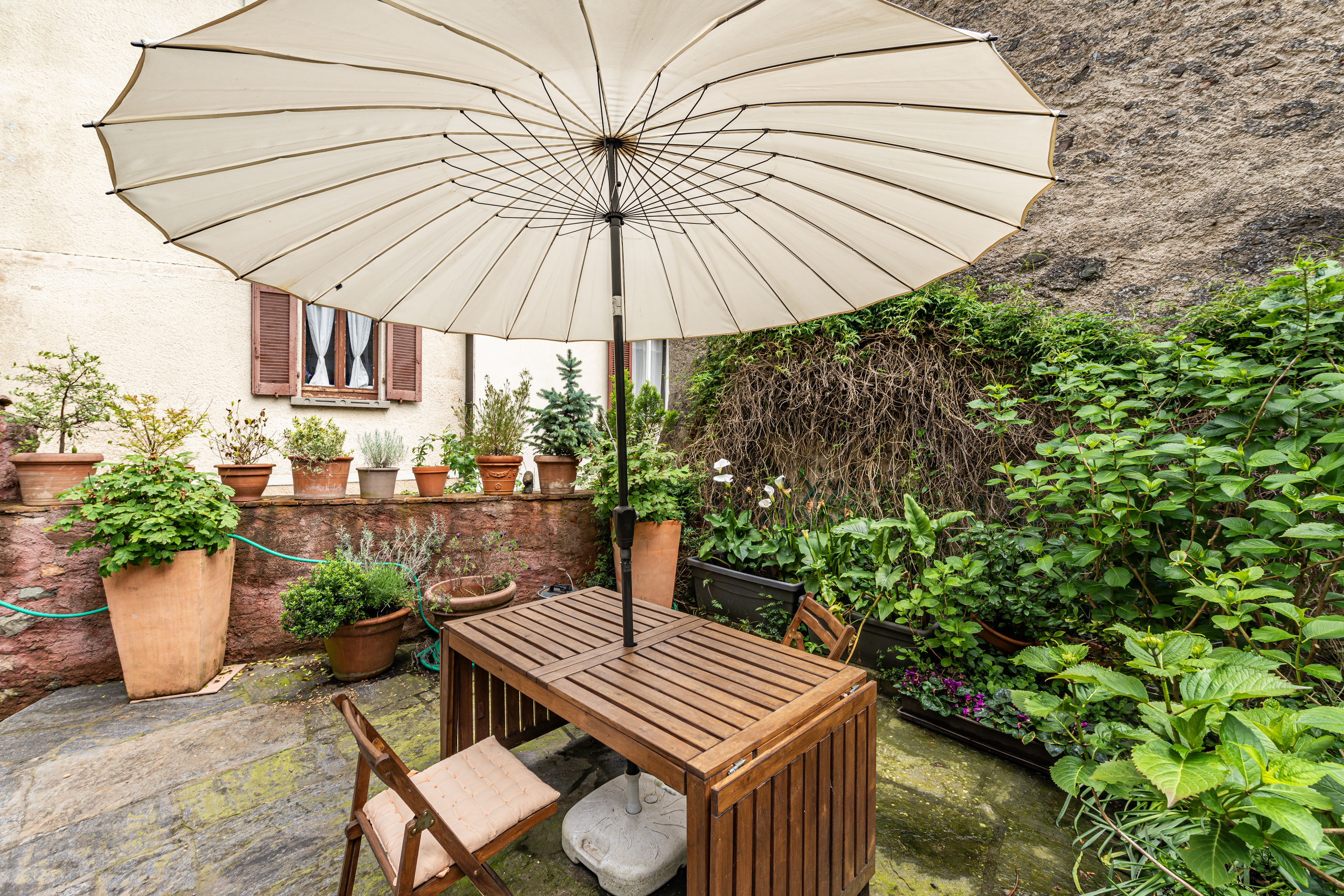 Gemütliche Gartenterrasse mit Schirm und Holztisch