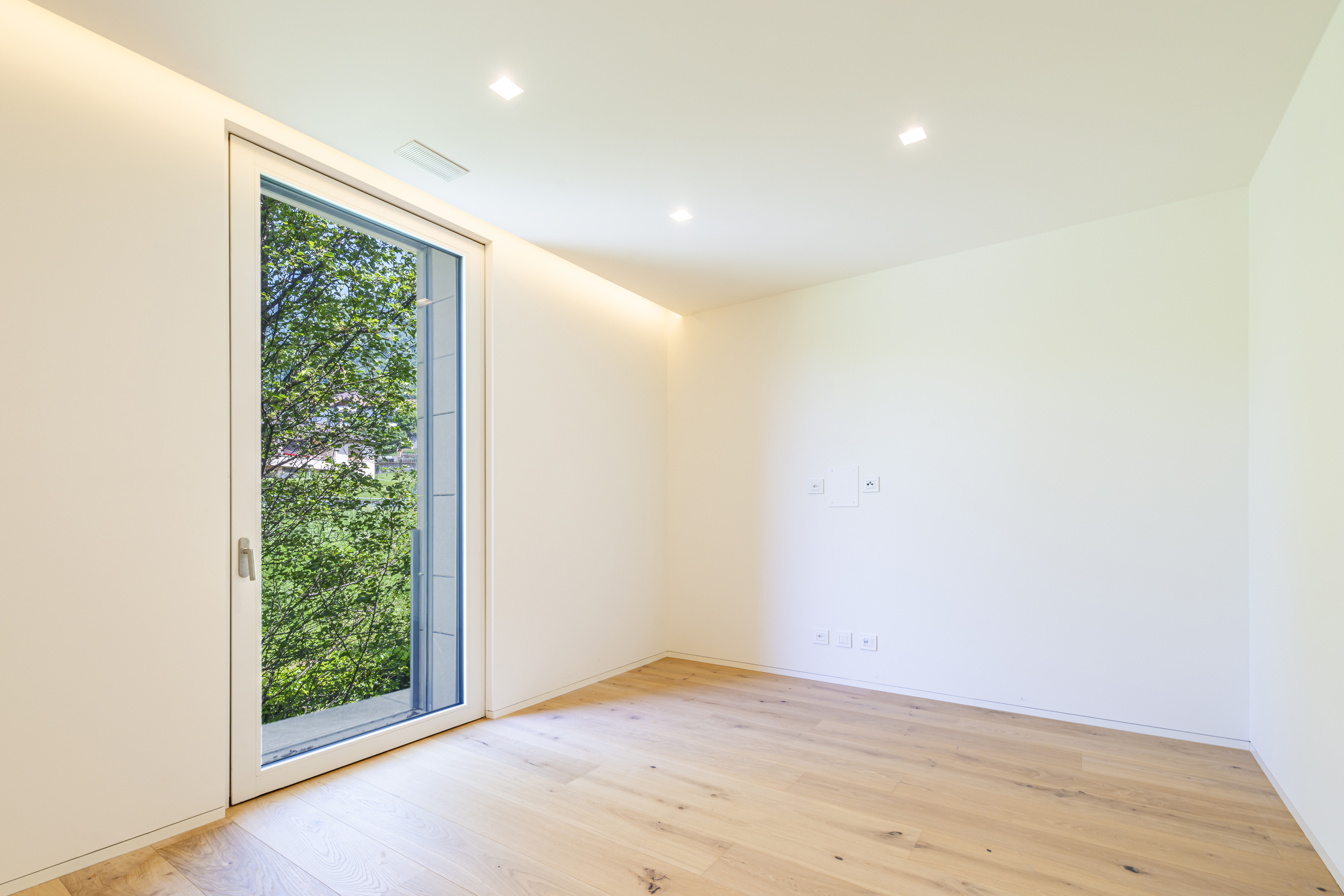 Heller leerer Raum mit Holzfußboden und großem Fenster