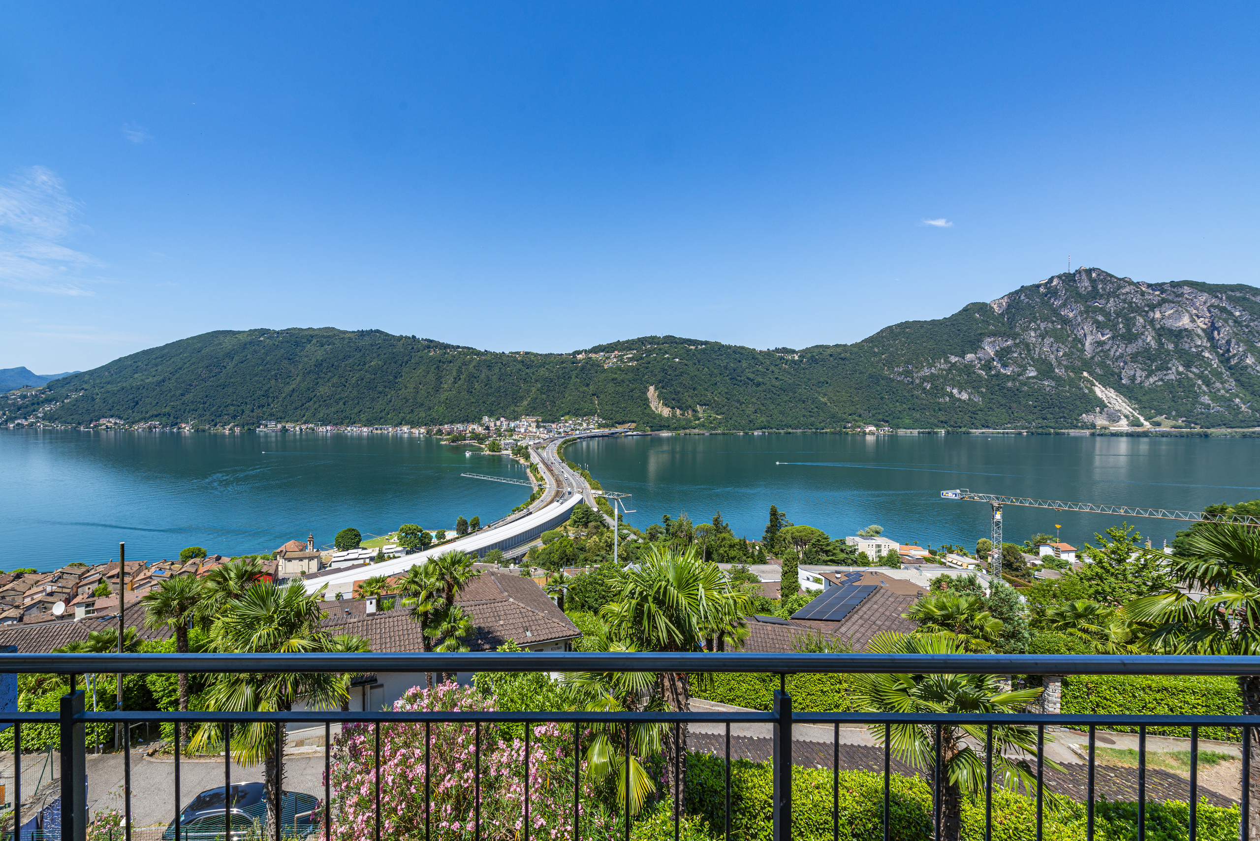 Aussicht von einer Terrasse oder einem Balkon auf See, Berge und Brücke