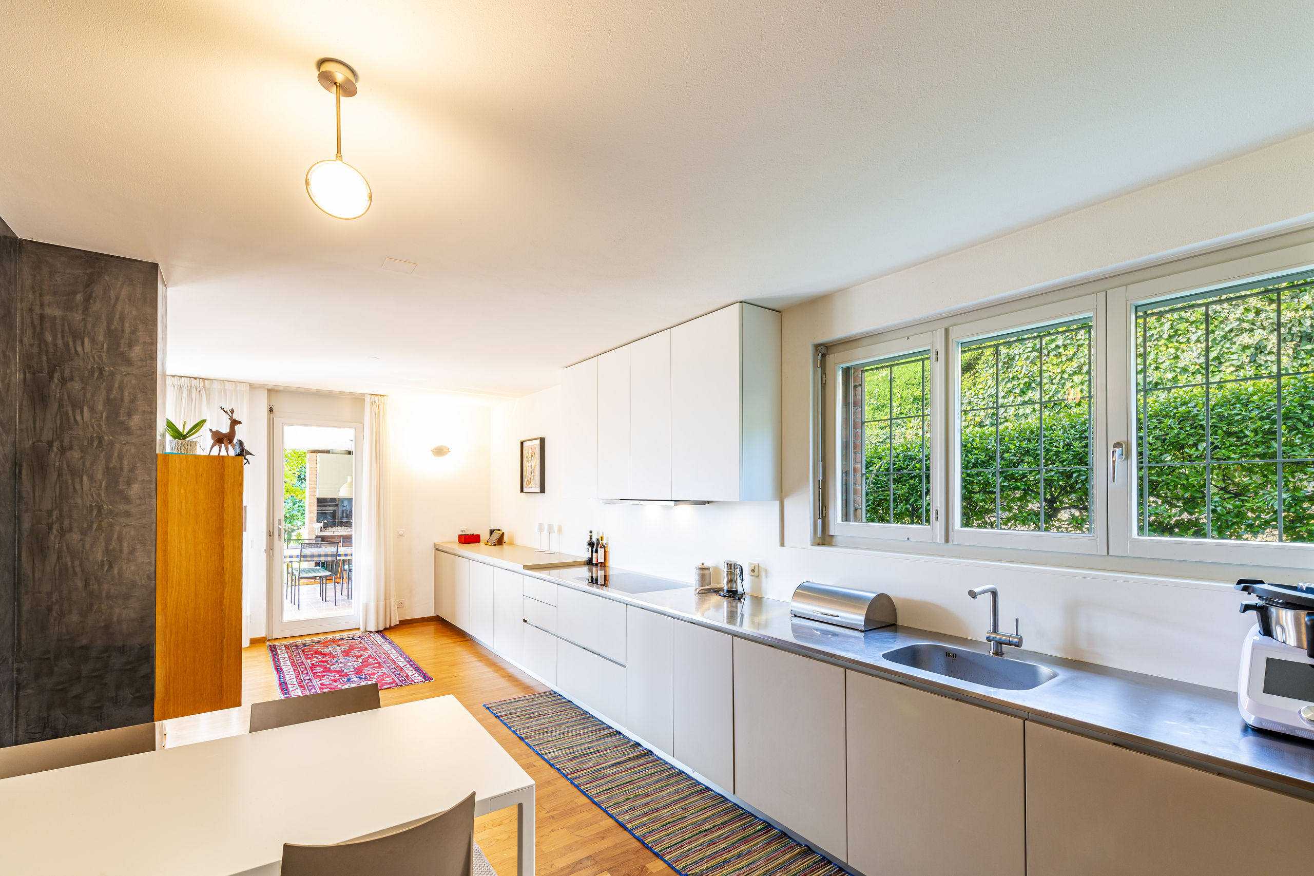 Helle, moderne Küche mit langem Unterschrank und Gartenblick
