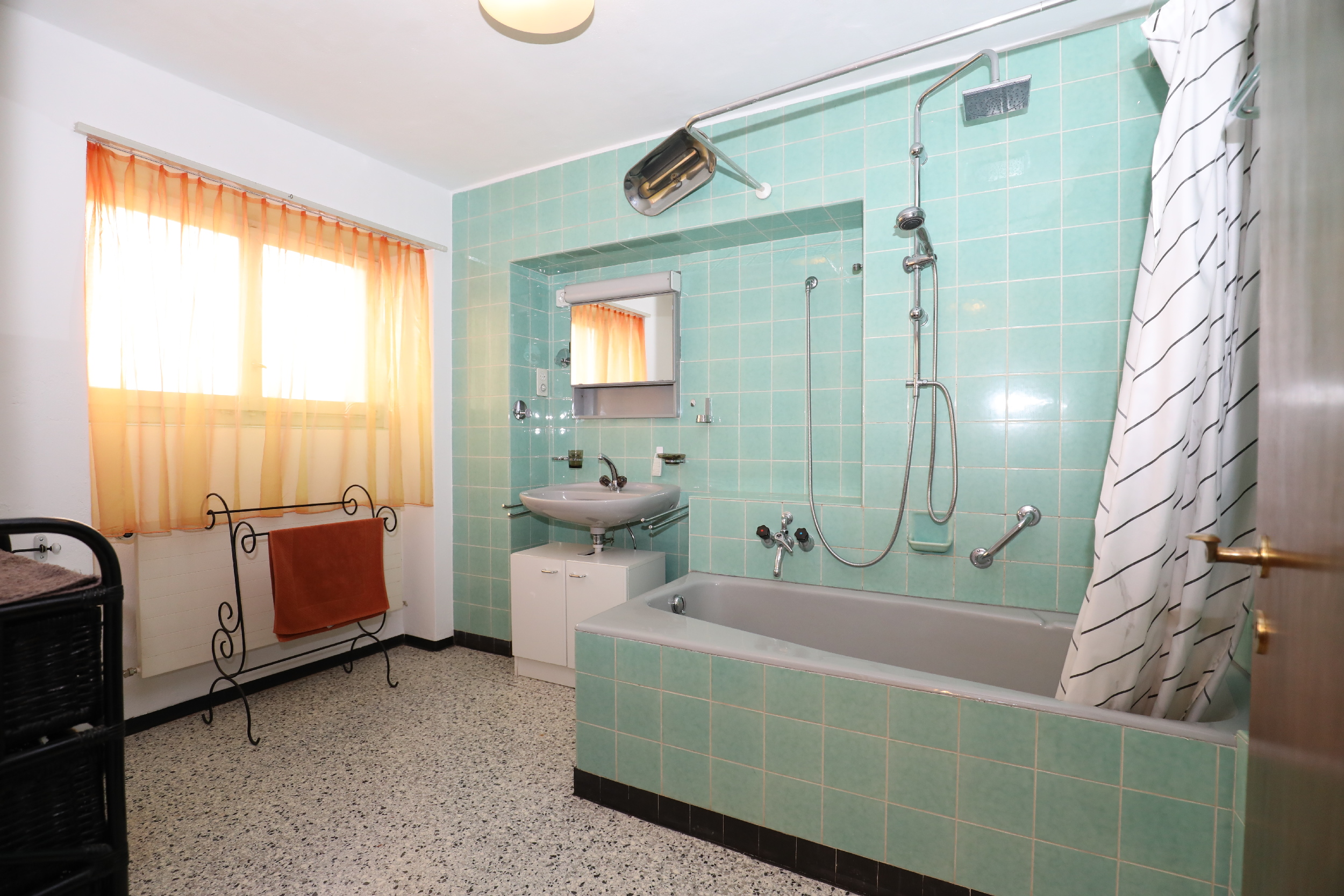 Badezimmer mit türkisfarbener Fliesenwand und Badewanne
