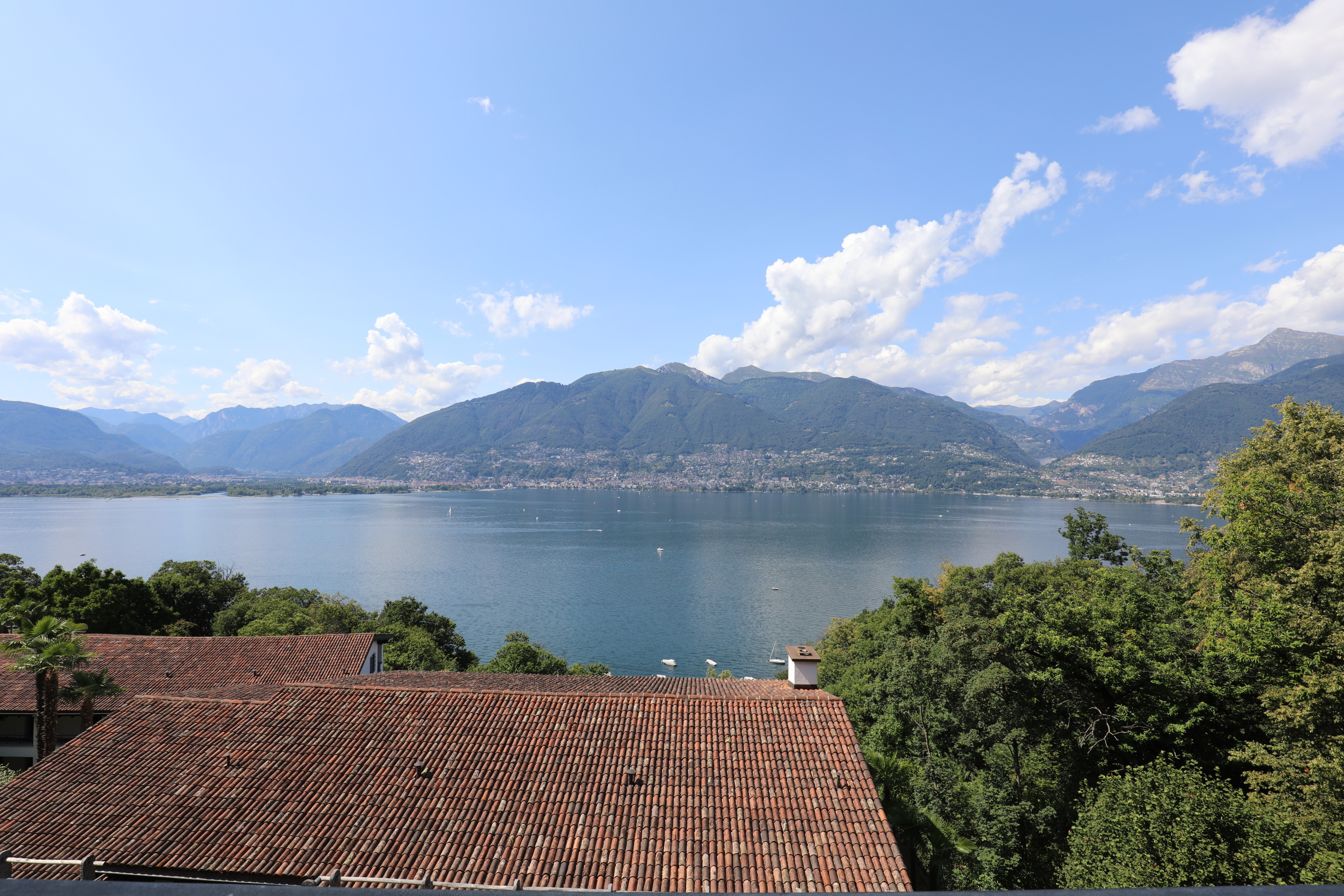 Seeblick mit Bergen und Ziegeldach
