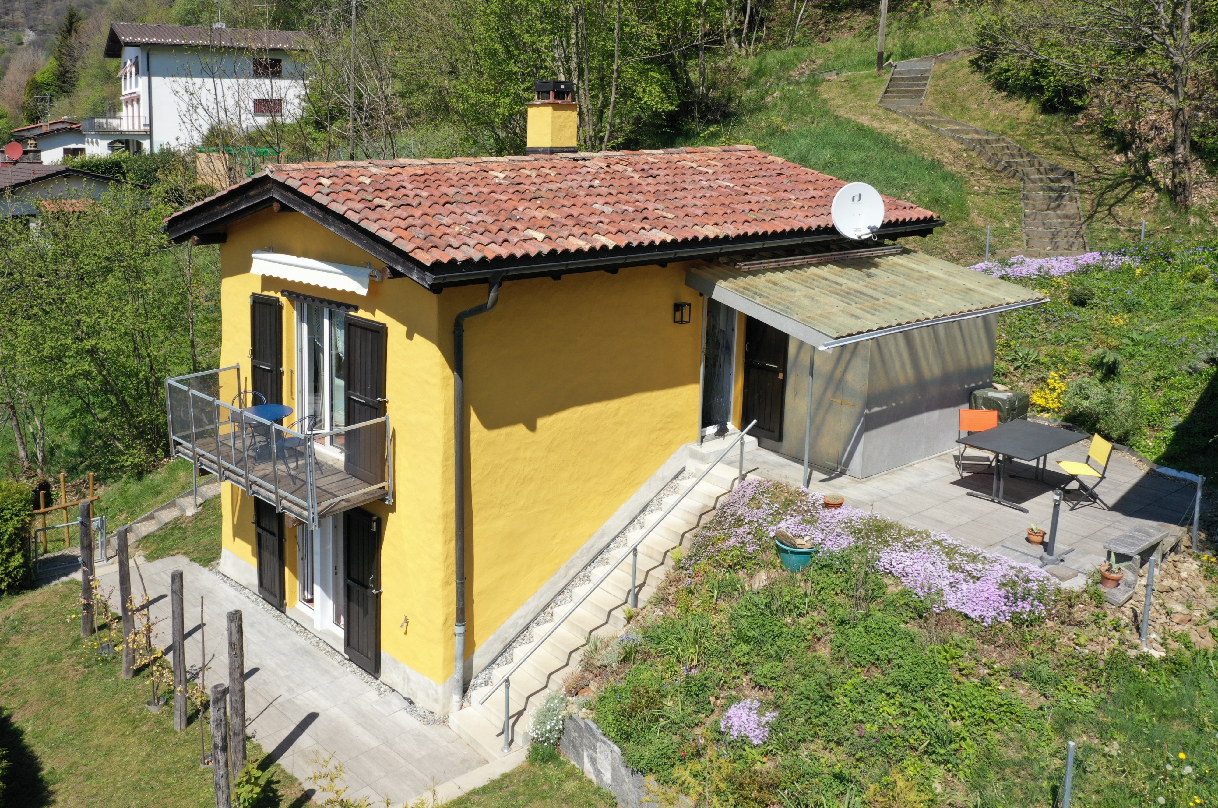 Gelbes Haus mit Terrasse und Gartenhang