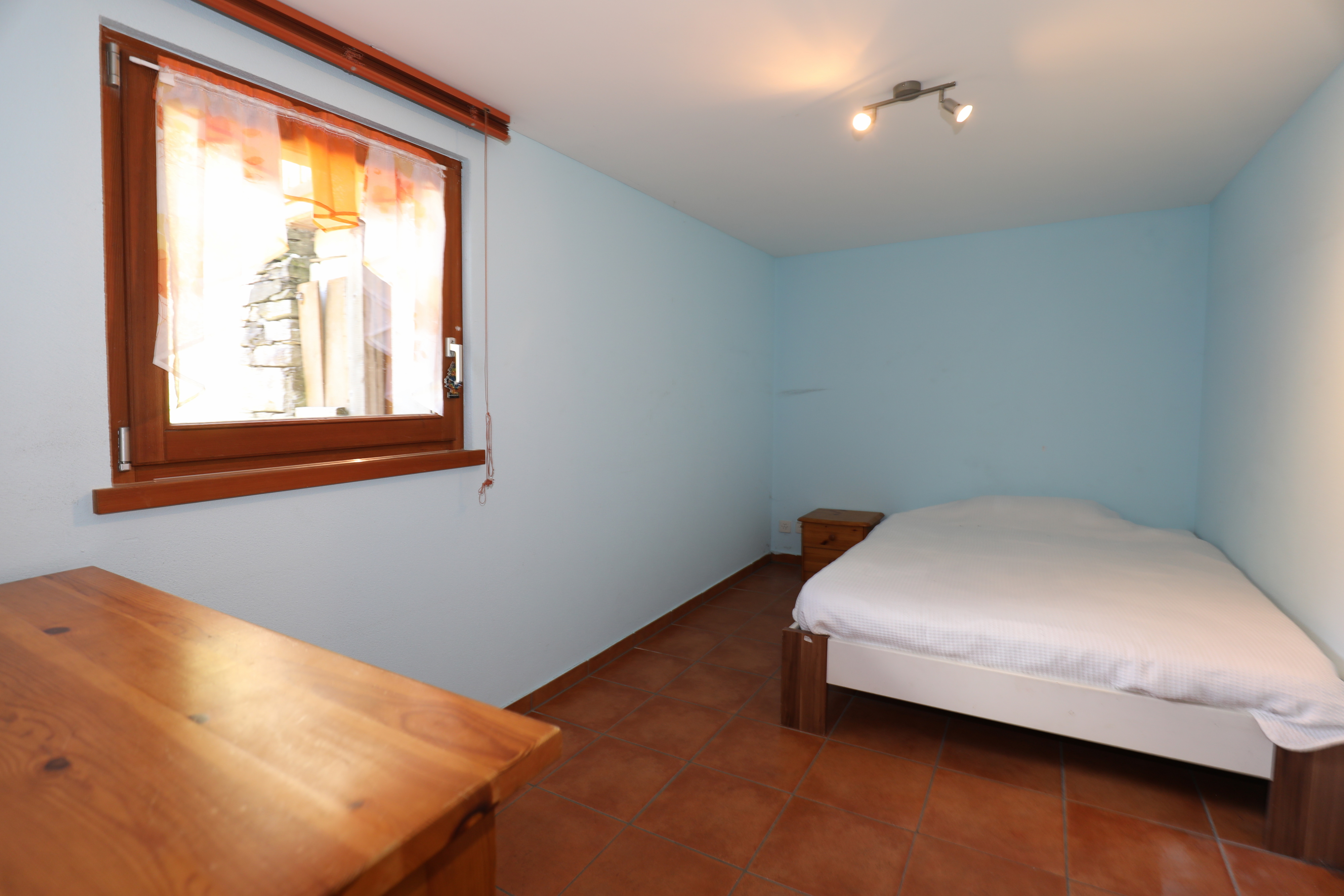 Kleines Schlafzimmer mit Bett und Fenster