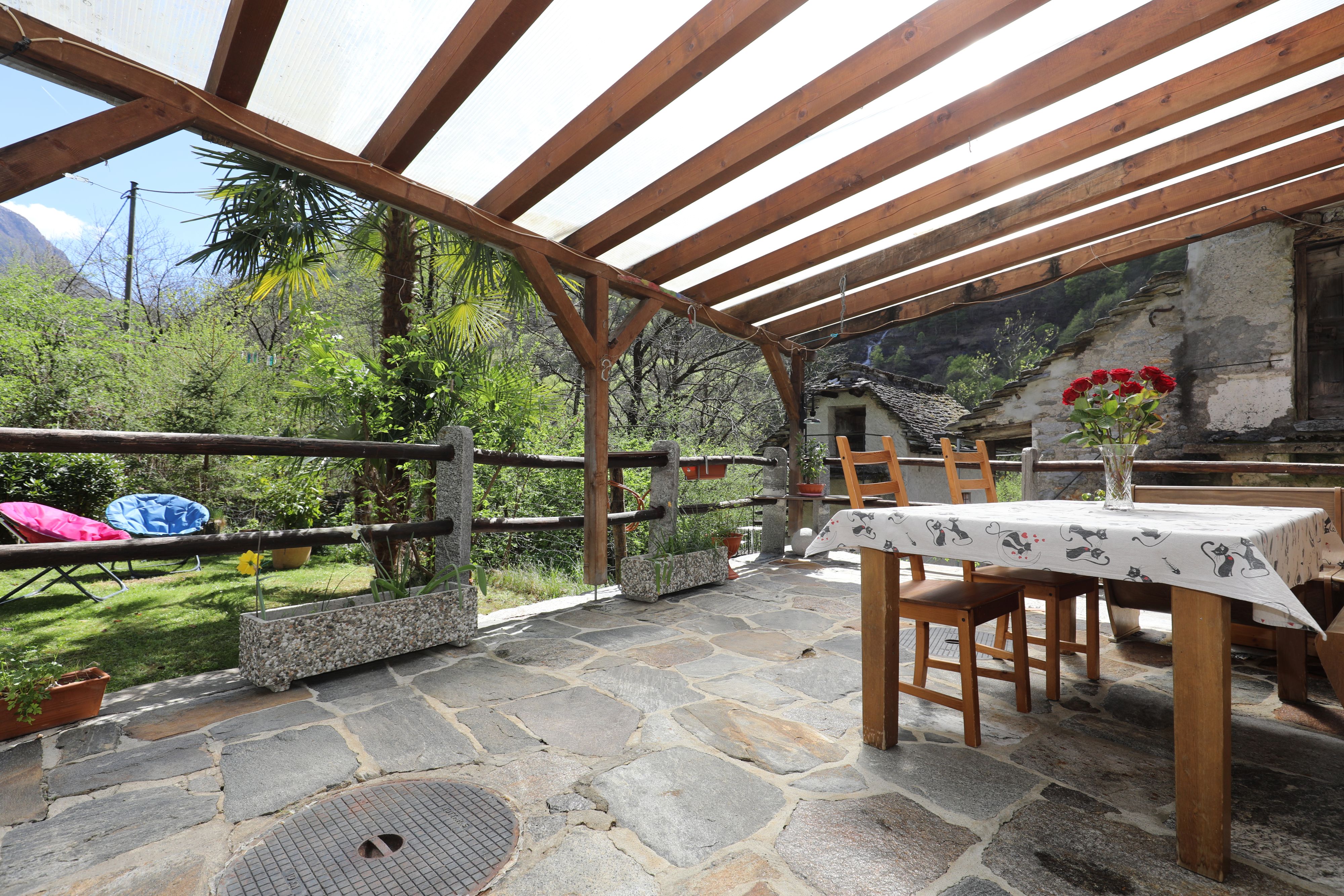 Überdachte Terrasse mit Berg- und Gartenblick