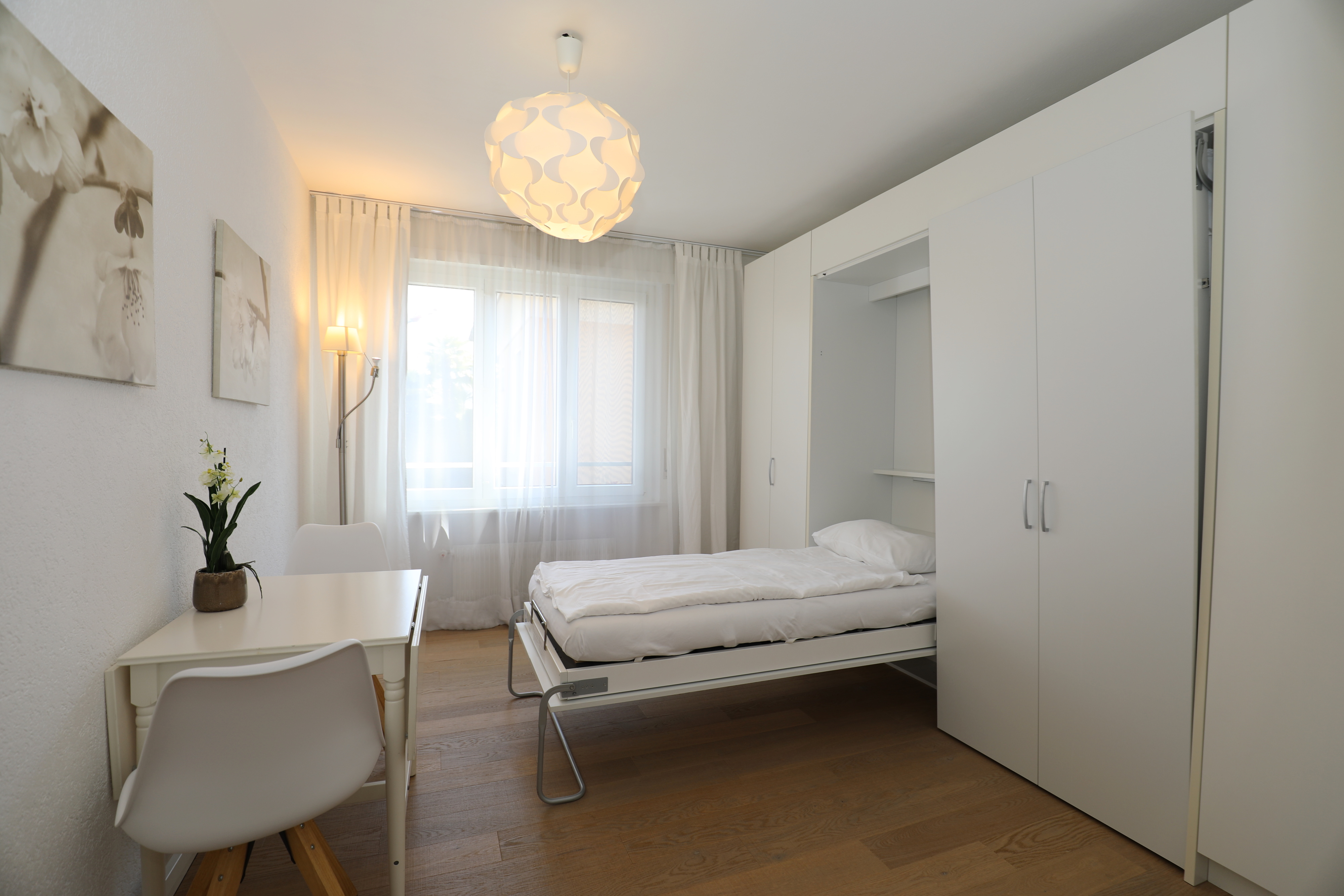 Helles Schlafzimmer mit Schrankbett und weißer Möblierung