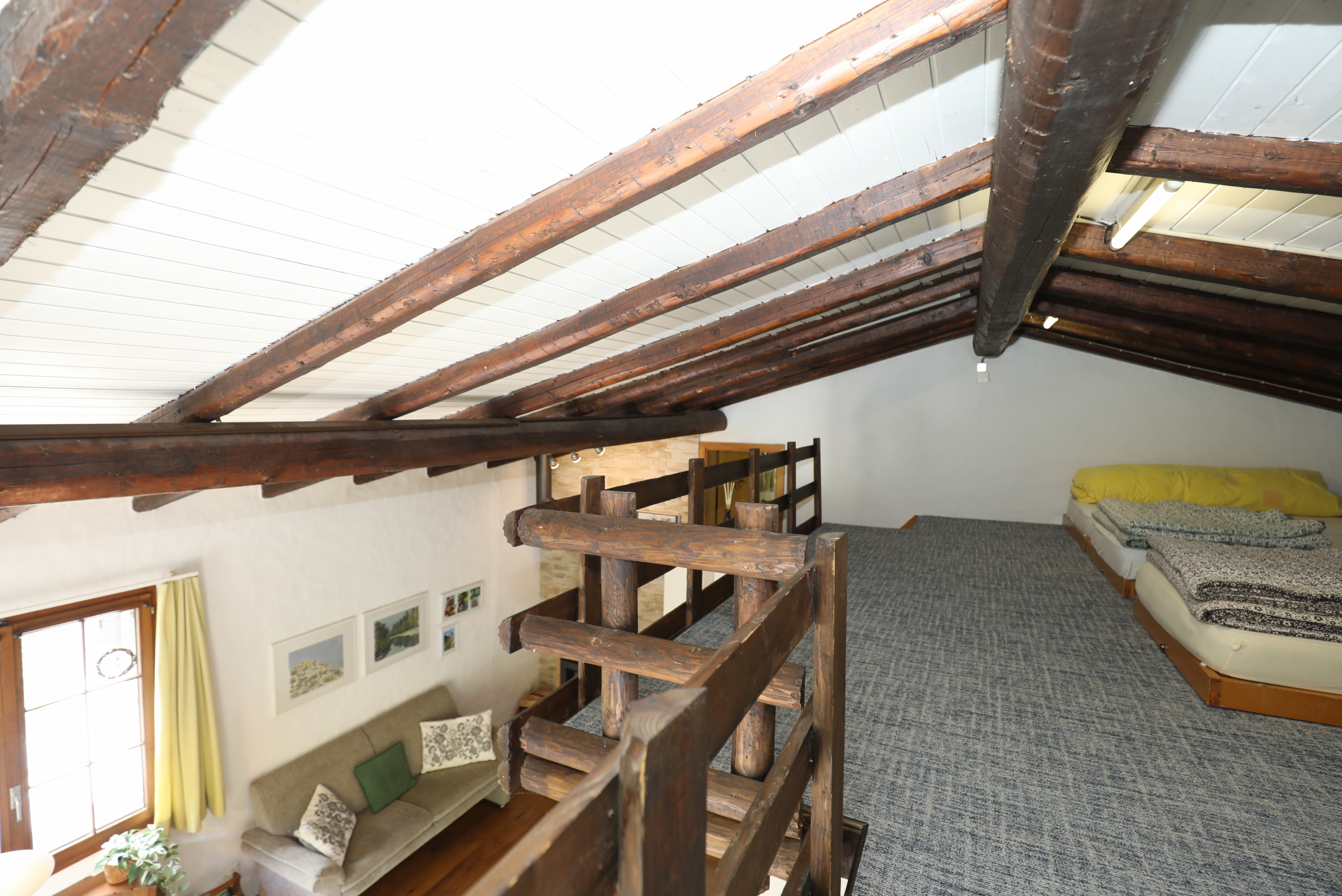 Galerieraum mit sichtbaren Holzbalken und Schlafbereich