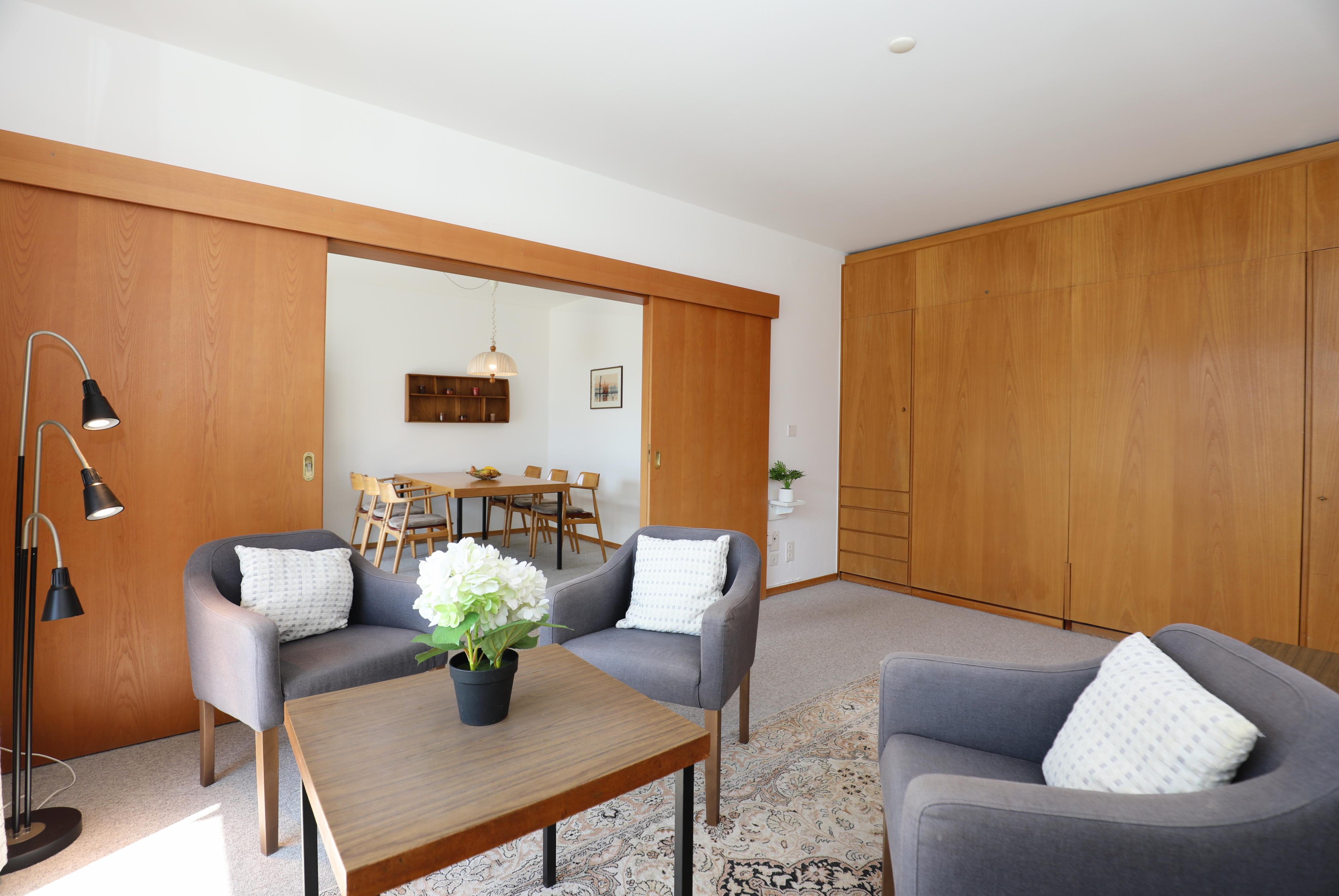 Wohnzimmer mit Holzpaneelen und Durchgang zum Essbereich