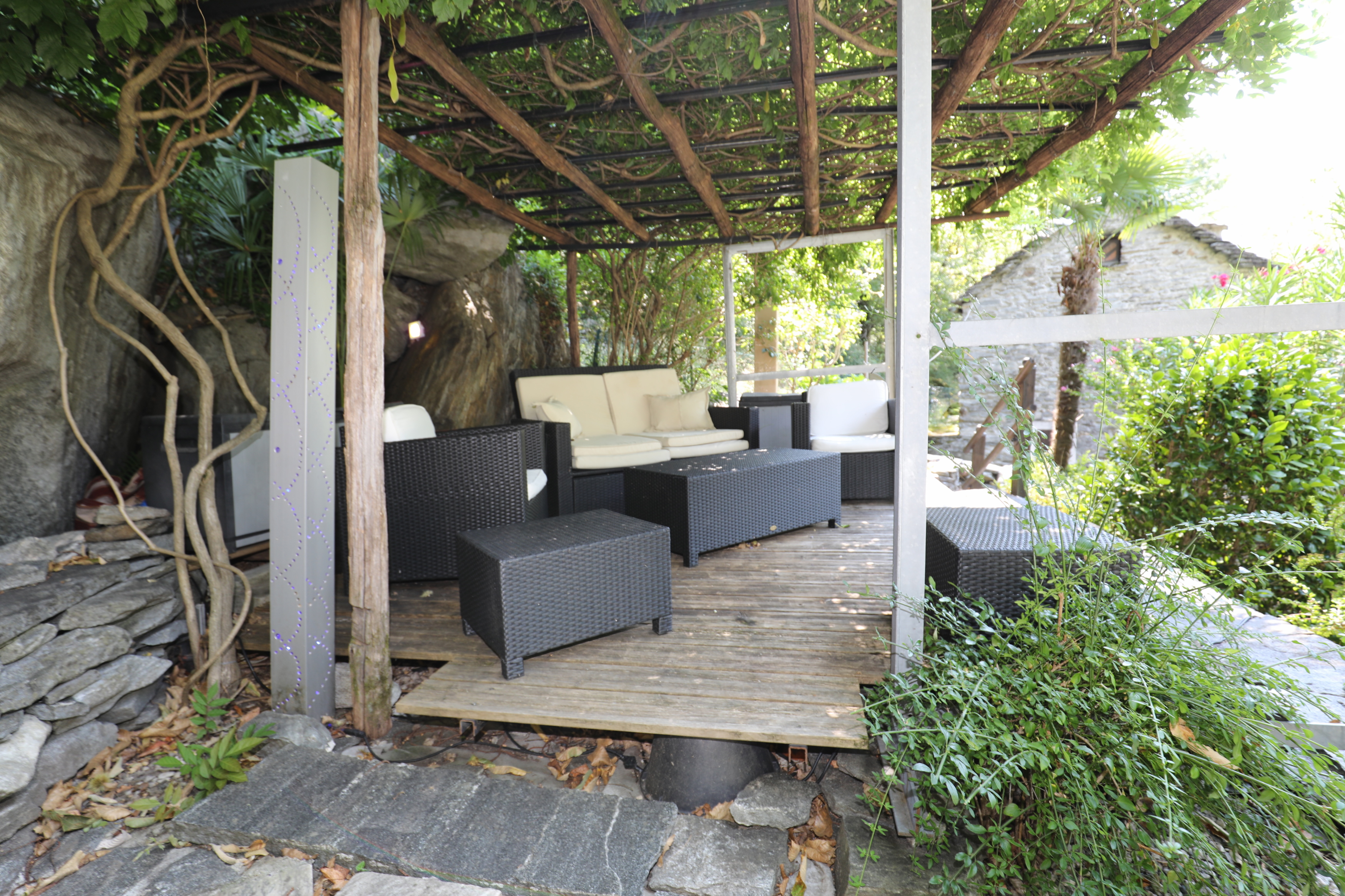 Überdachte Gartenlounge mit Natur- und Holzoptik
