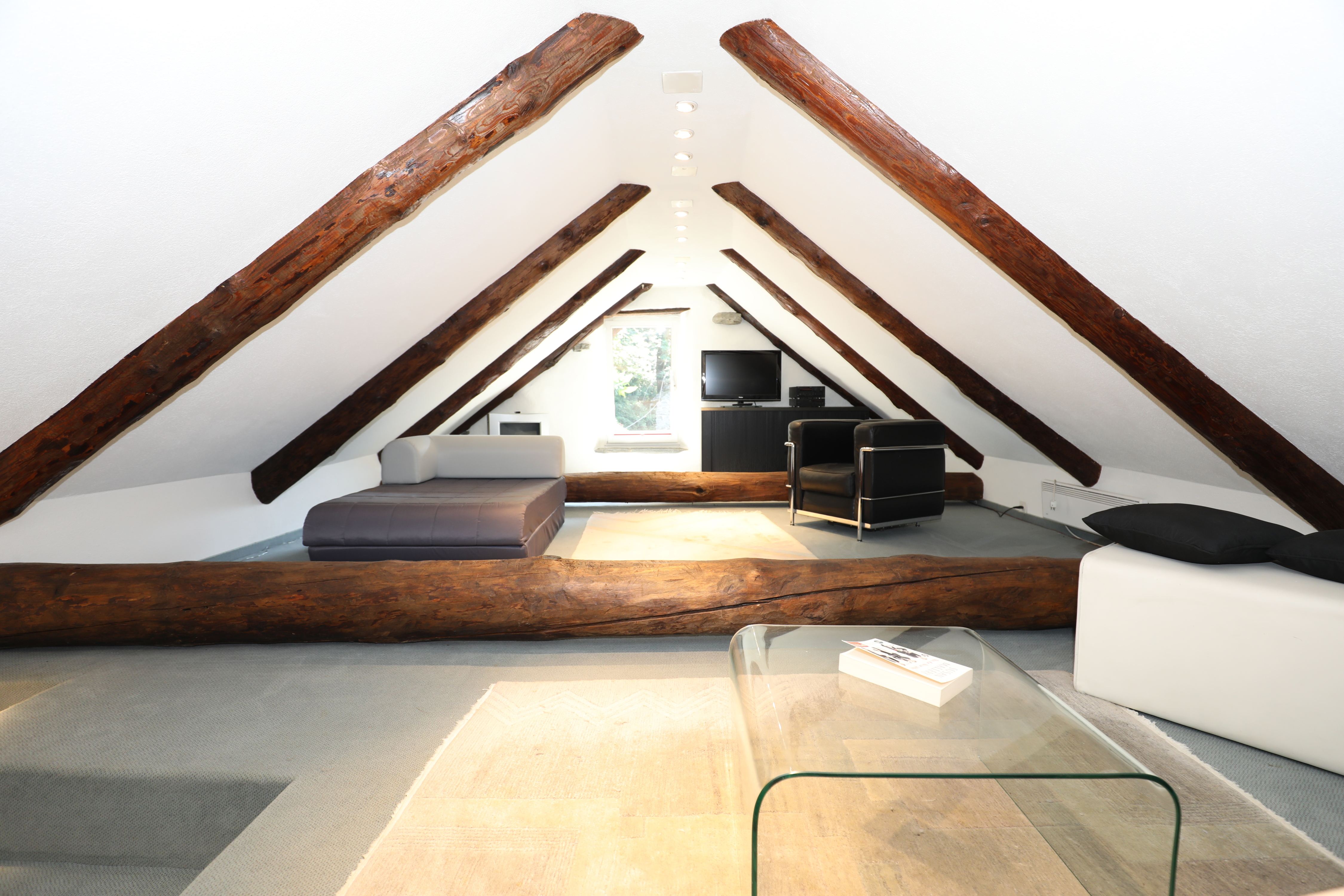 Dachgeschoss-Lounge mit sichtbaren Holzbalken