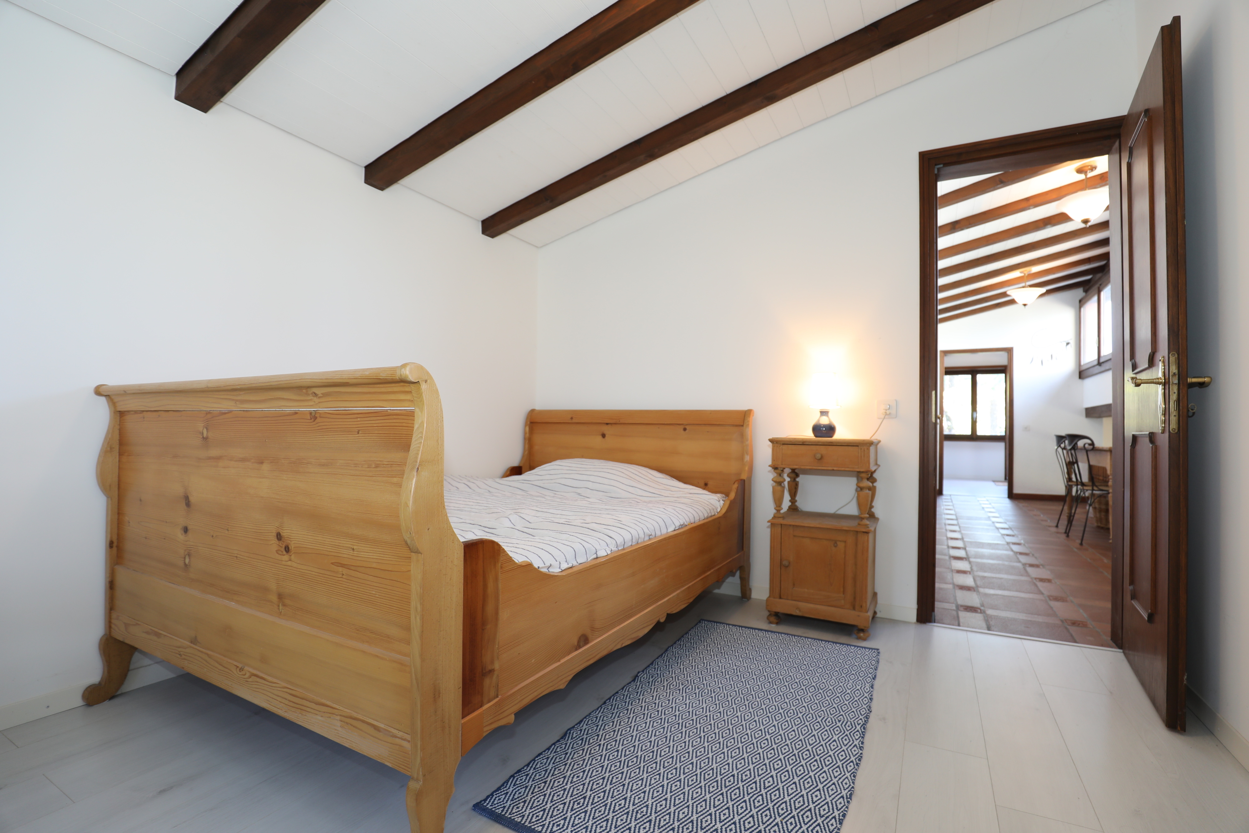 Schlafzimmer mit Holzbett und sichtbarem Durchgang