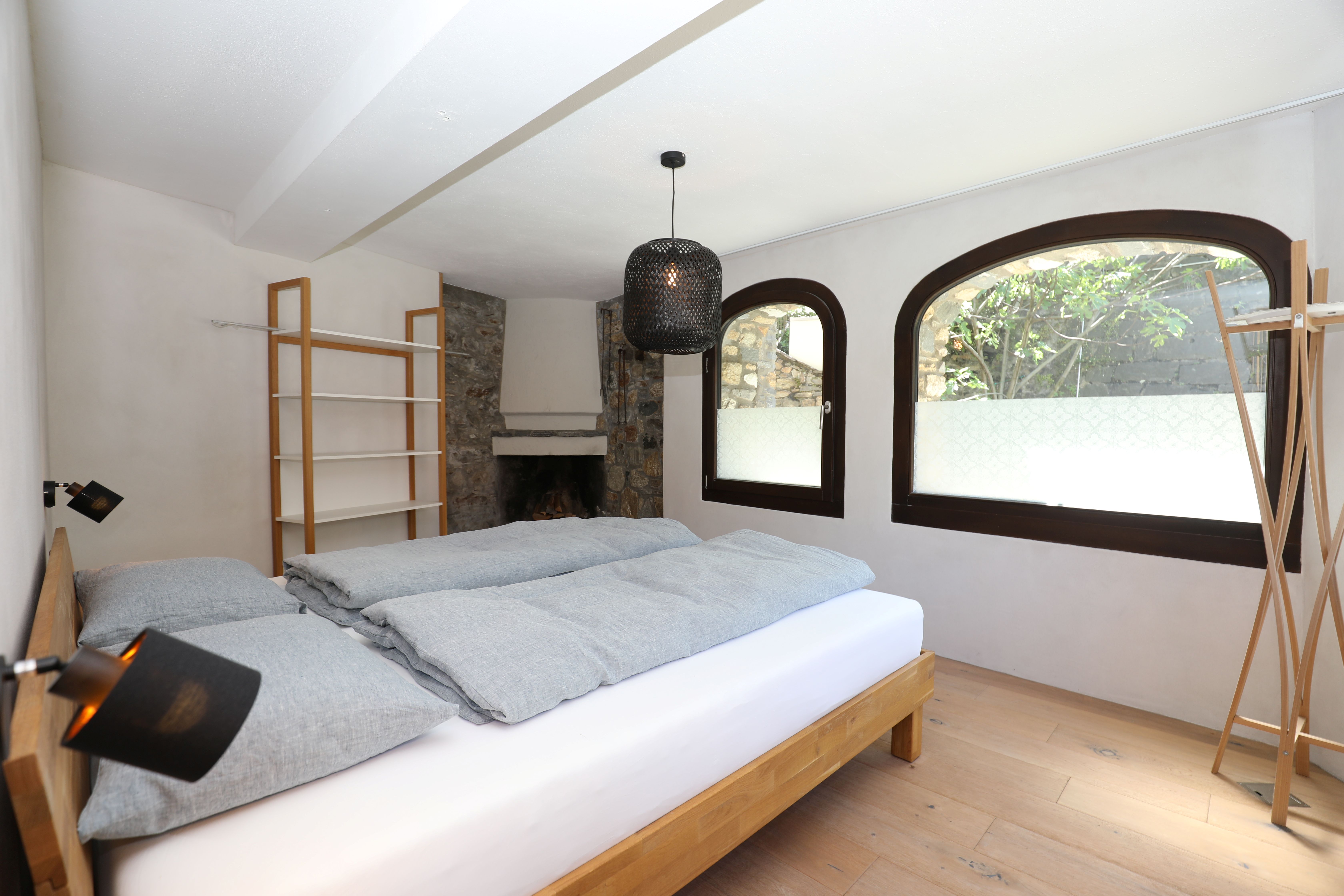 Helles Schlafzimmer mit Natursteinakzent und Rundbogenfenstern