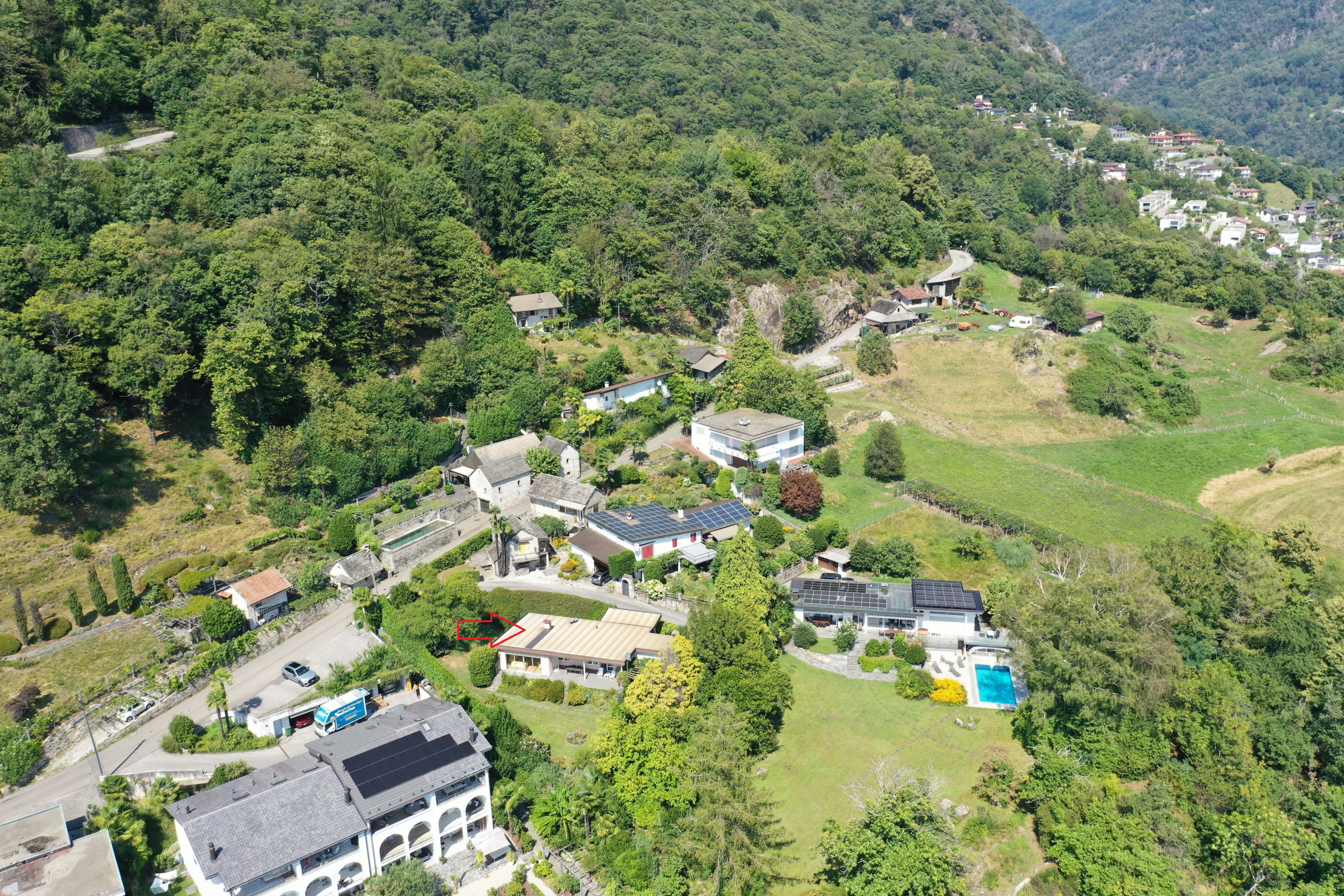 Luftaufnahme eines ländlichen Hanggrundstücks mit Pool und Solardächern