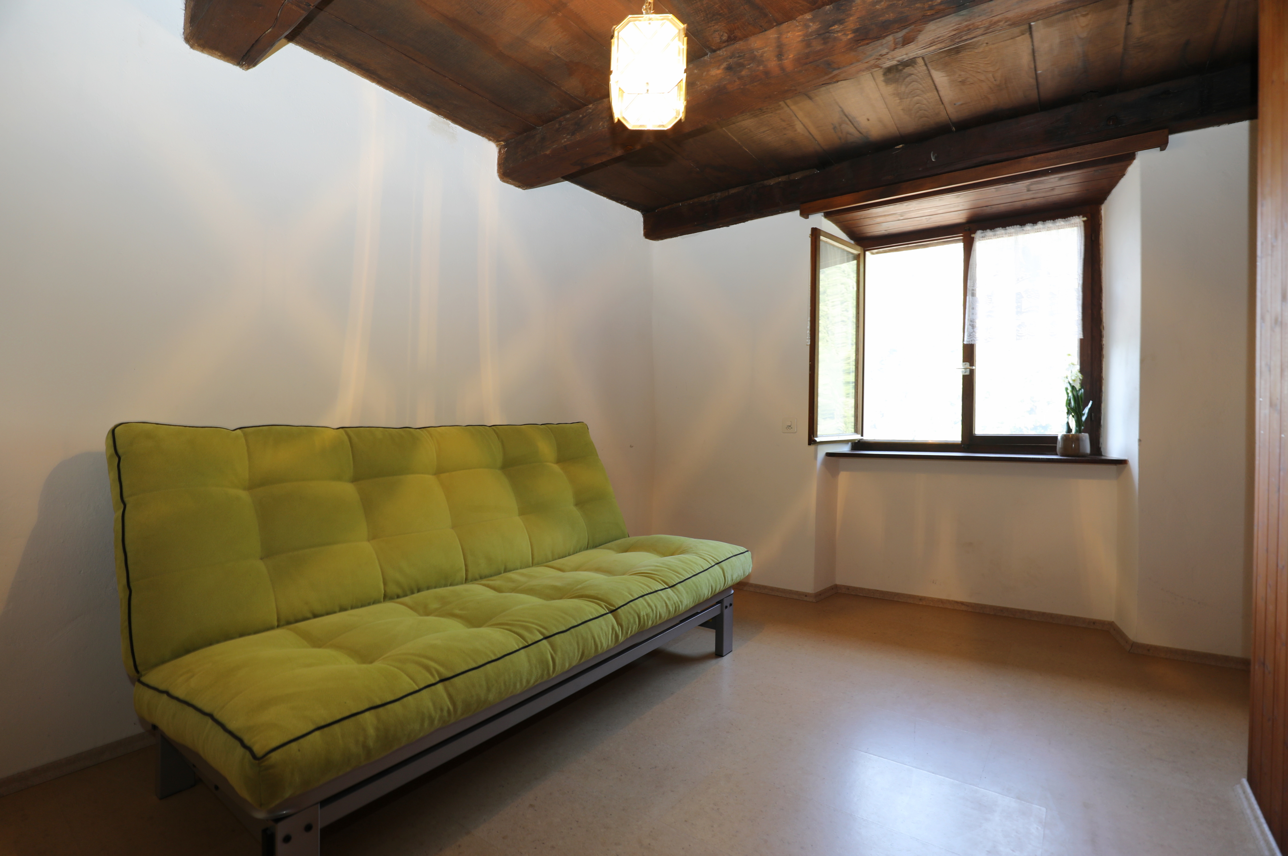Kleines Zimmer mit Futon und sichtbaren Holzbalken