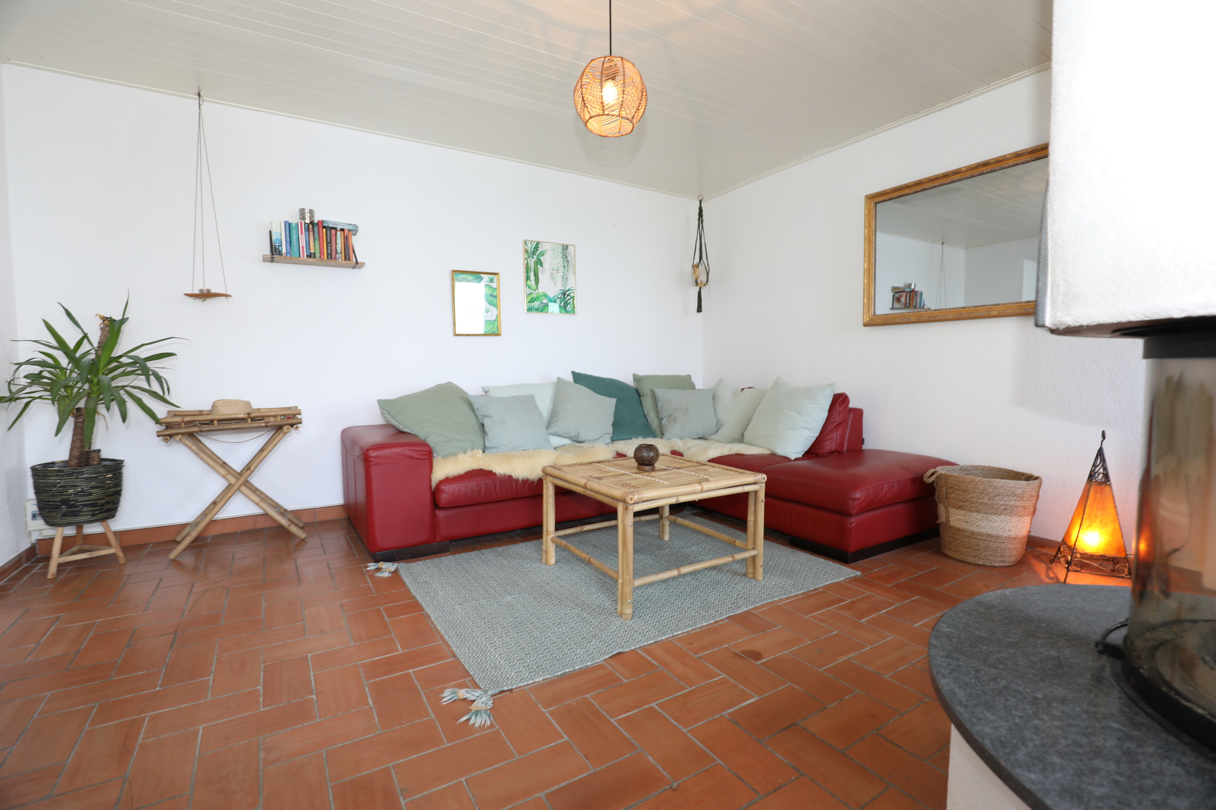 Gemütliches Wohnzimmer mit Terrakottafliesen und rotem Ecksofa
