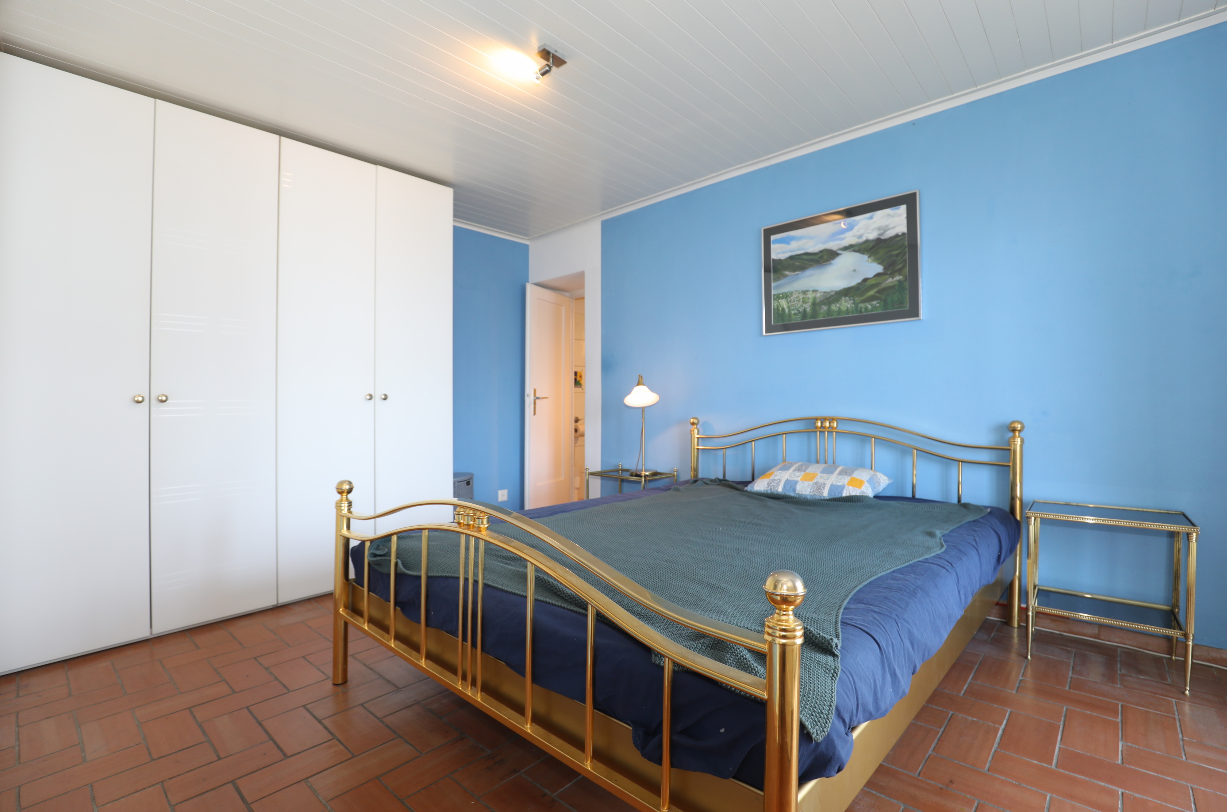 Schlafzimmer mit blau gestrichenen Wänden und Messingbett
