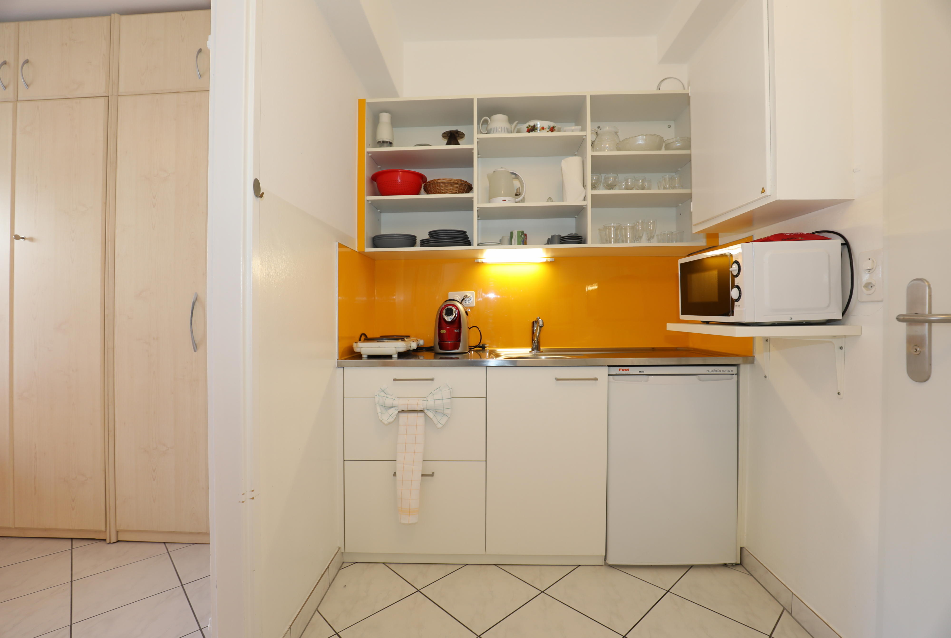 Kleine Küchenzeile mit orangener Rückwand