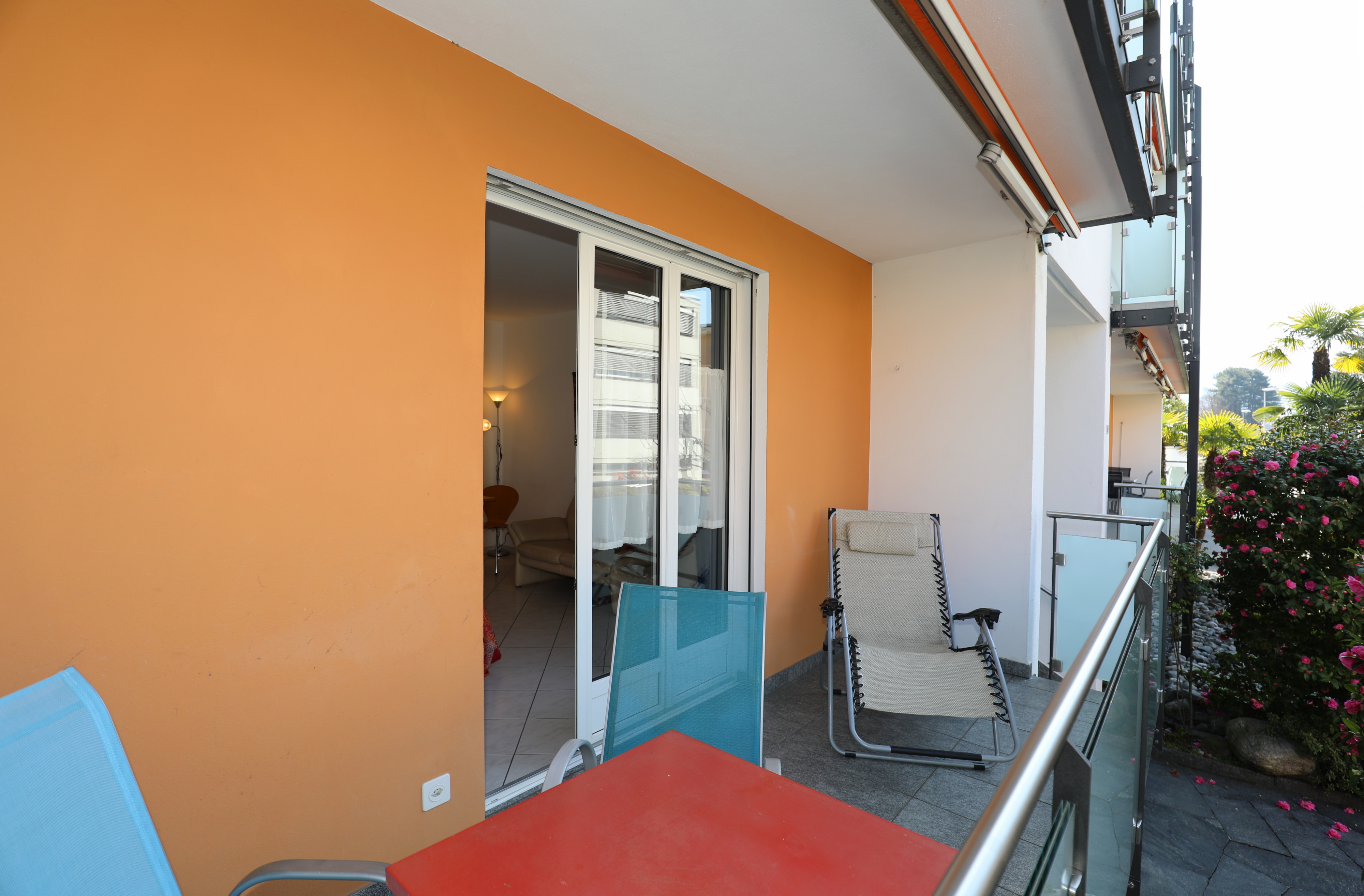 Balkon mit Sitzmöbeln vor einer farbigen Fassade