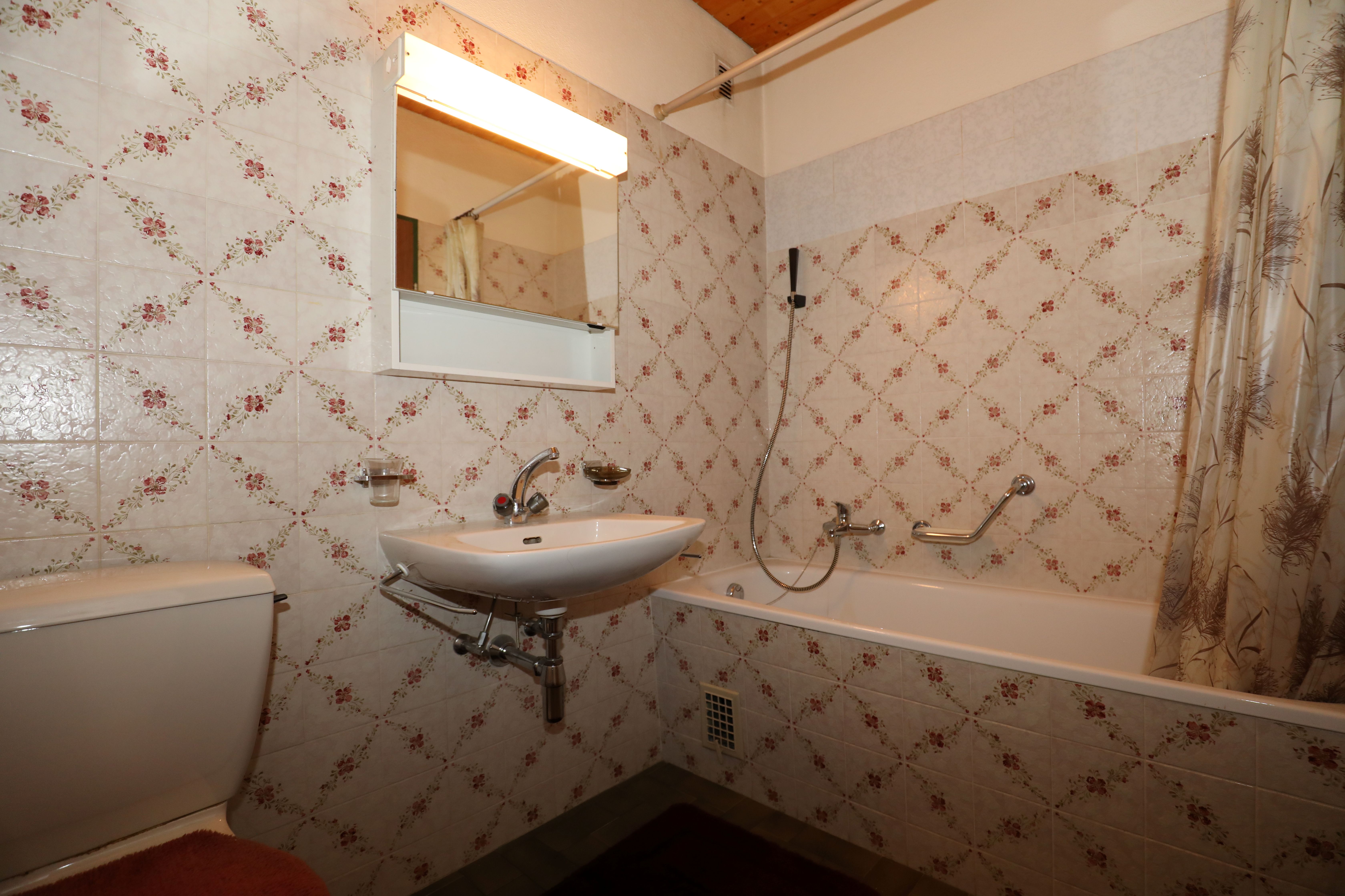 Retro-Badezimmer mit Wanne und floral gefliesten Wänden