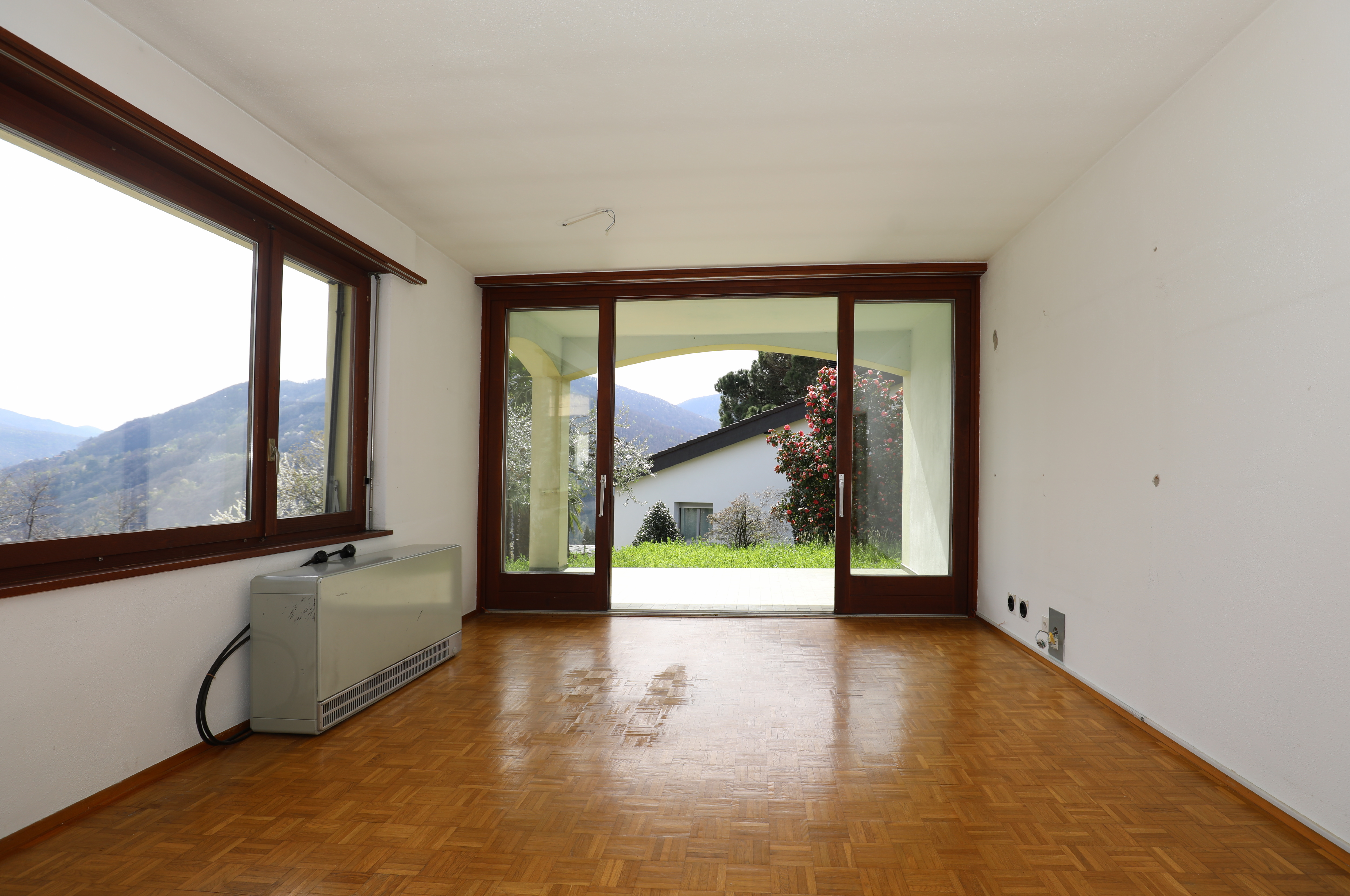 Leerer Wohnraum mit großen Fensterfronten und Bergblick