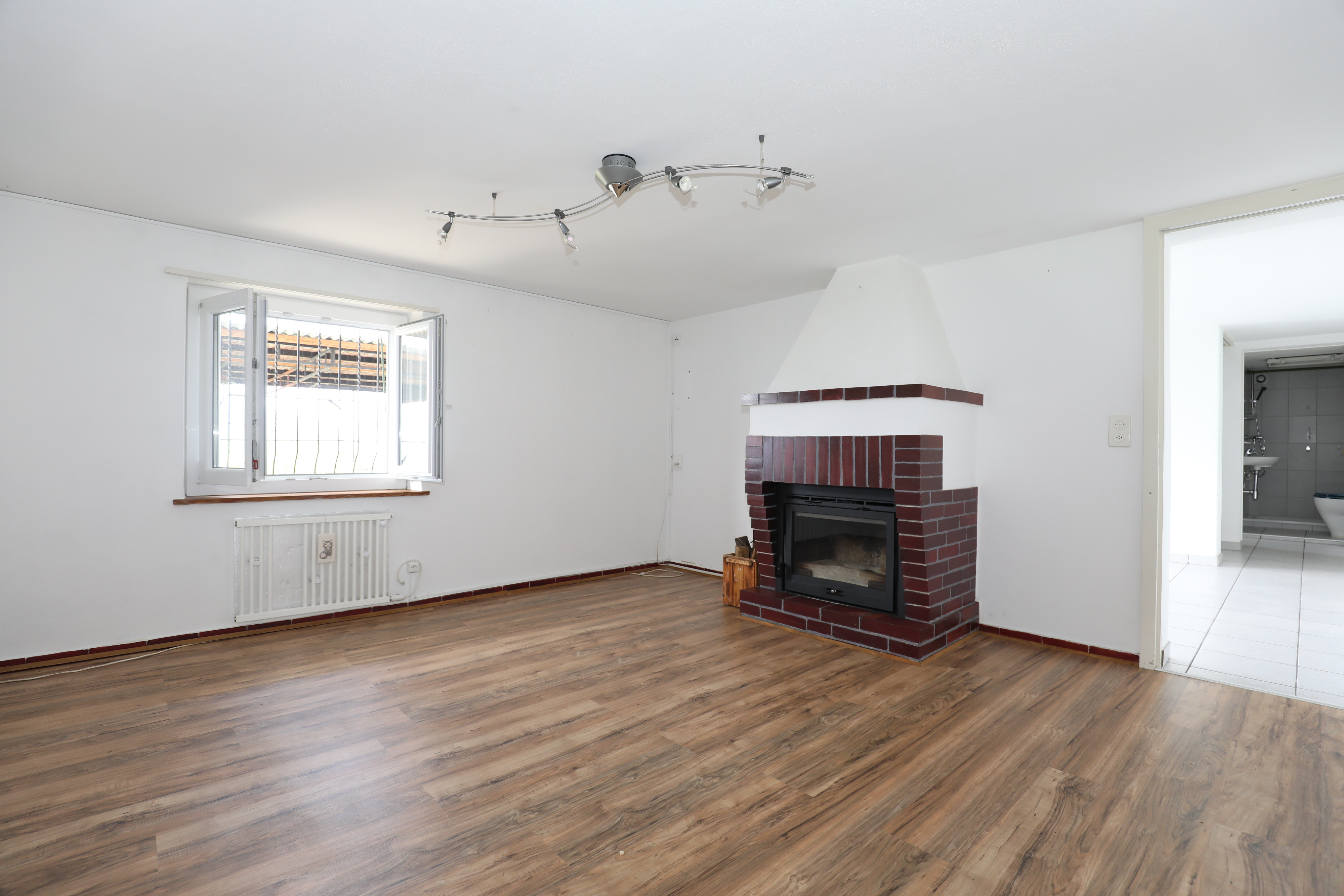Wohnzimmer mit Kamin und Holzoptik-Boden