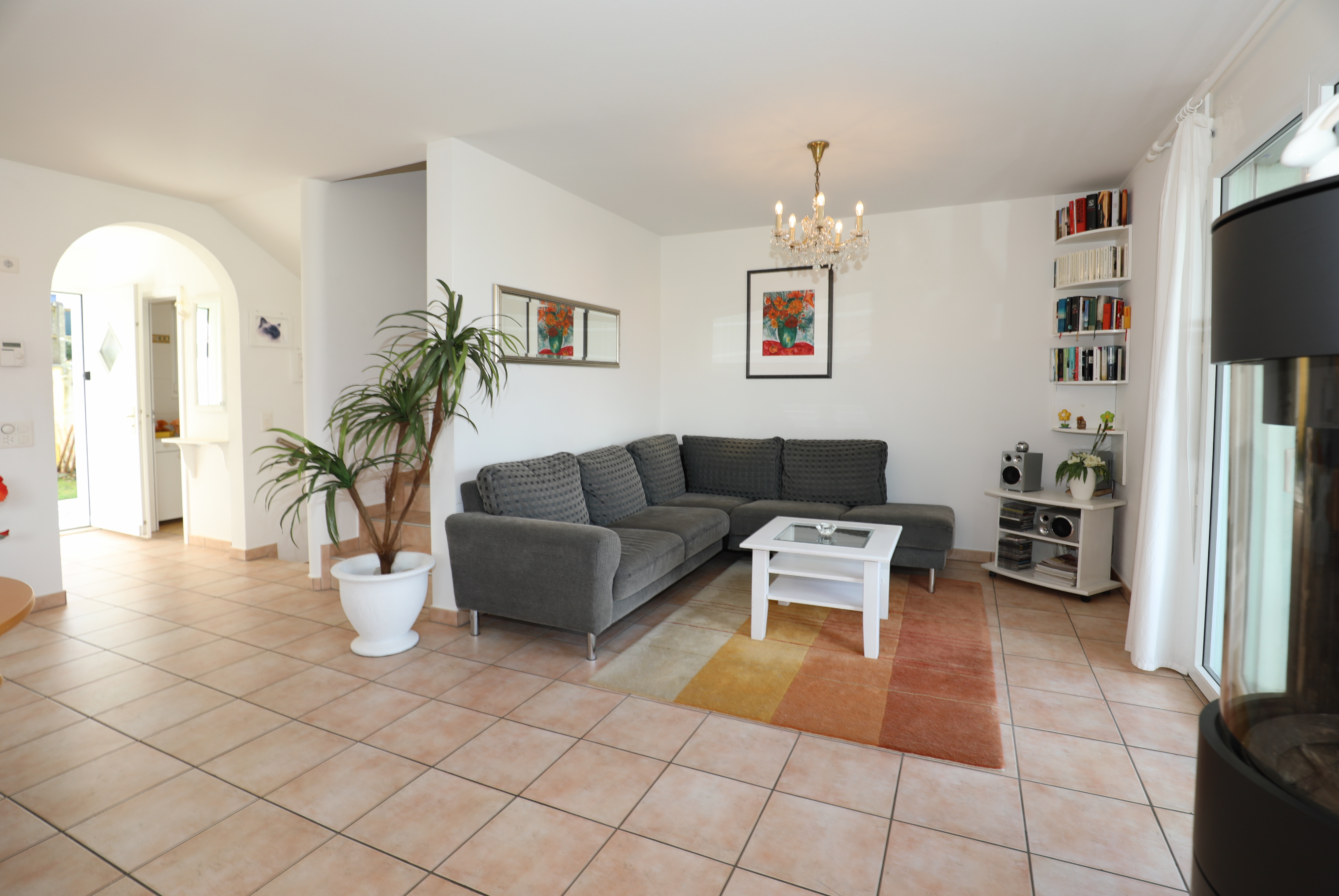Wohnzimmer mit Terrakottafliesen und grauer Eckcouch