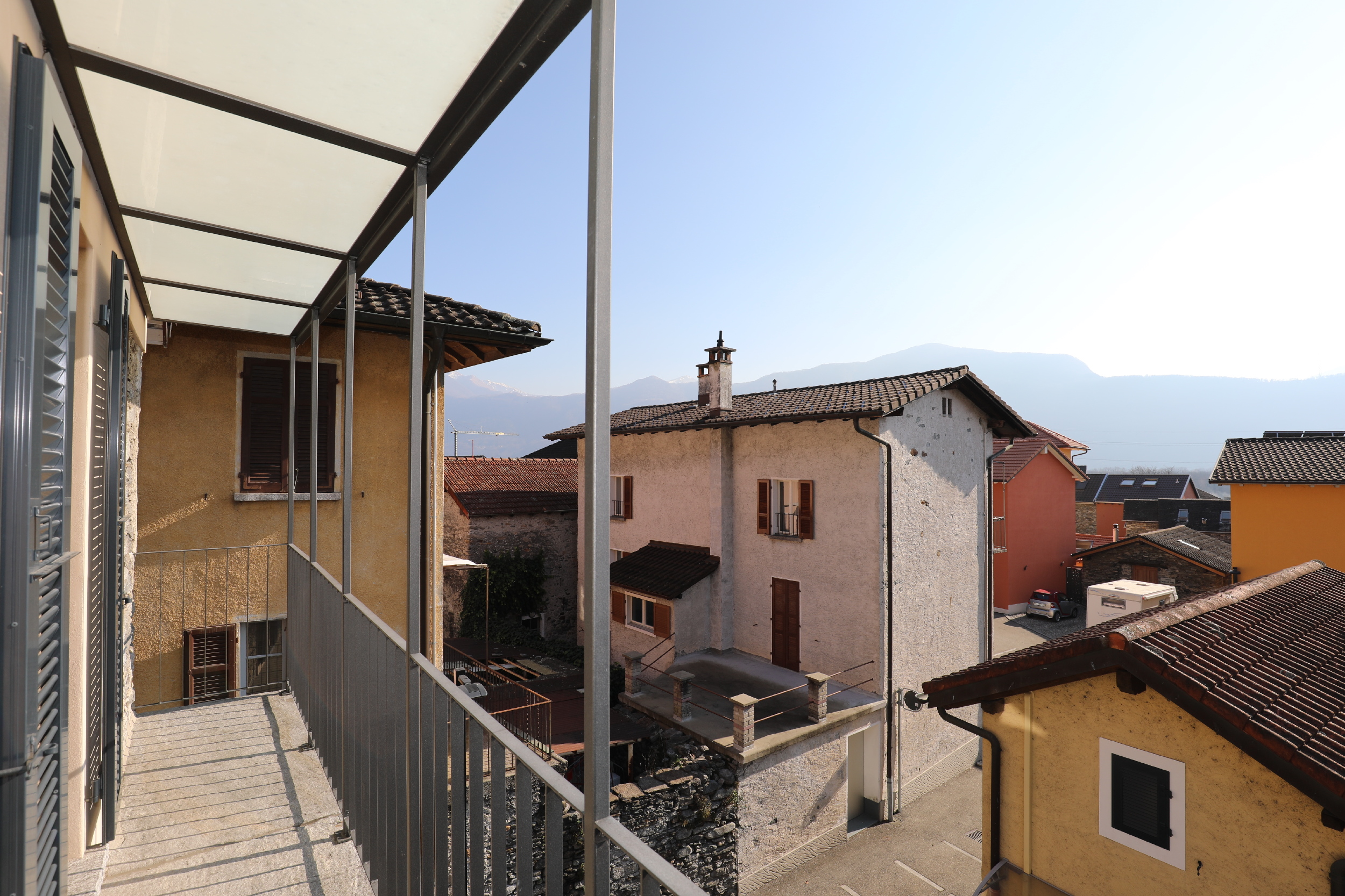 Balkon mit Blick auf Nachbarhäuser und Berge