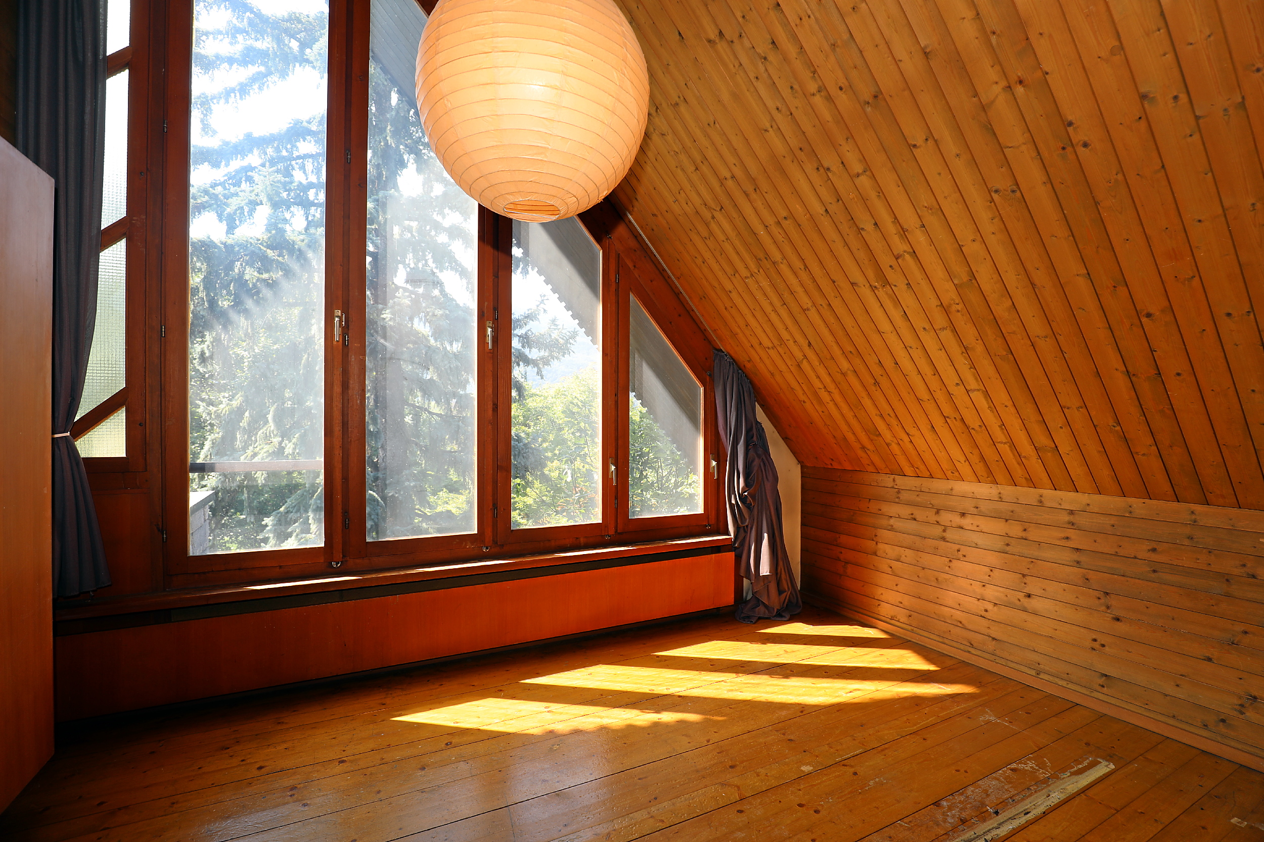 Dachzimmer mit Holzverkleidung und großen Fenstern