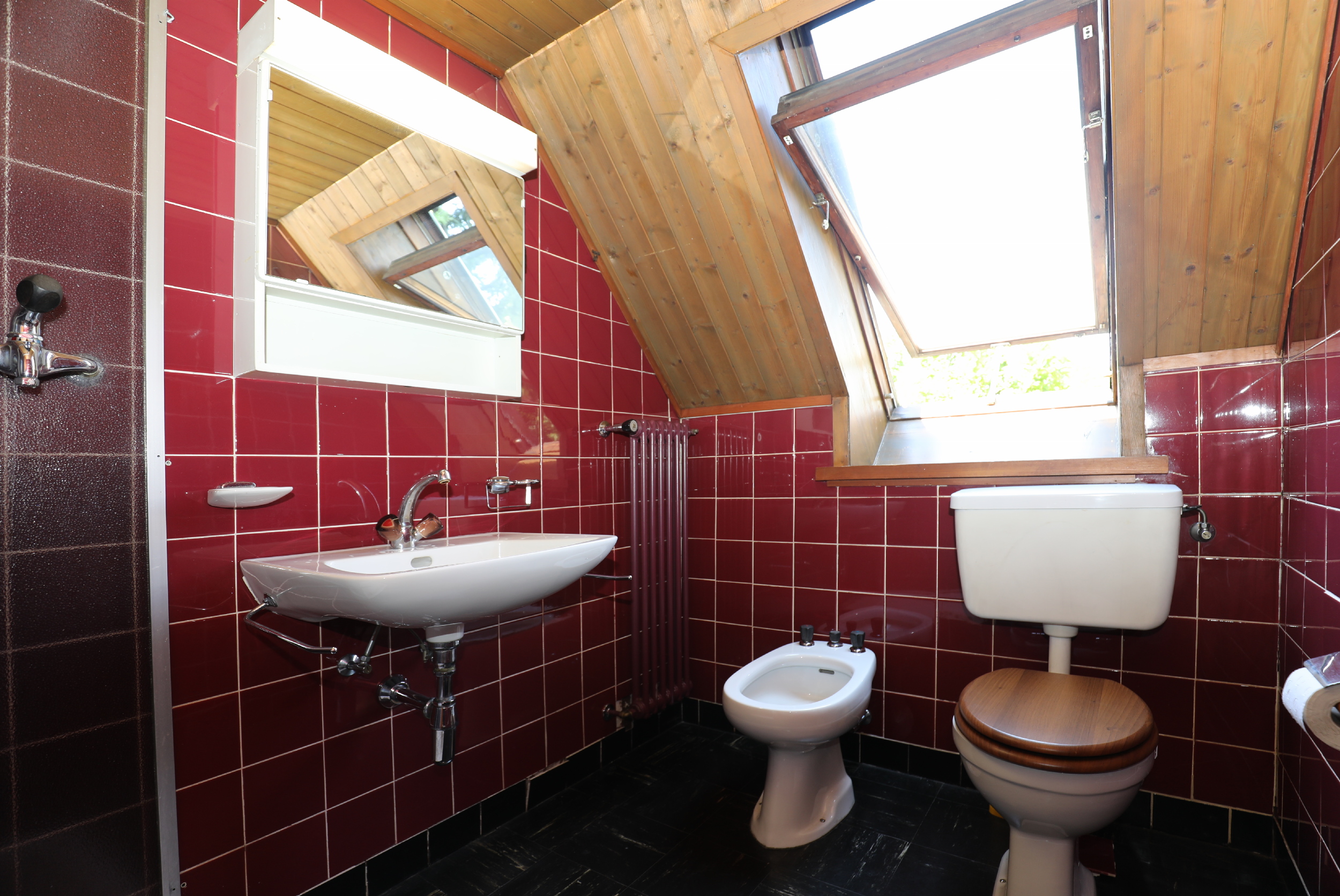 Badezimmer mit Dachfenster und roter Fliesenverkleidung