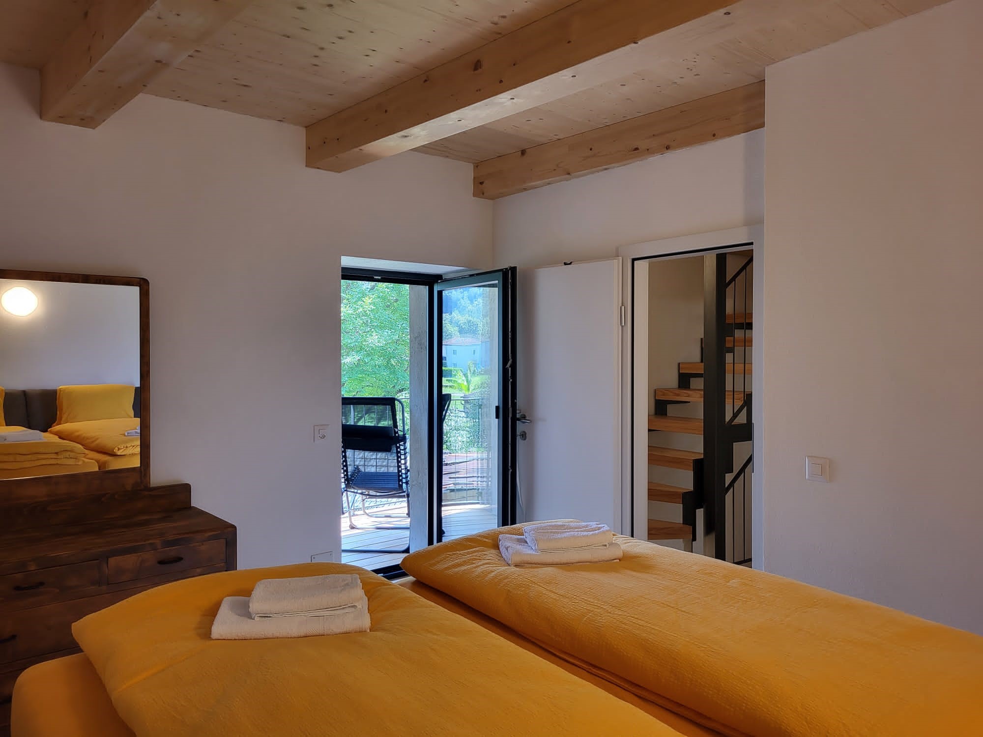 Schlafzimmer mit Holzbalkendecke und Balkonzugang