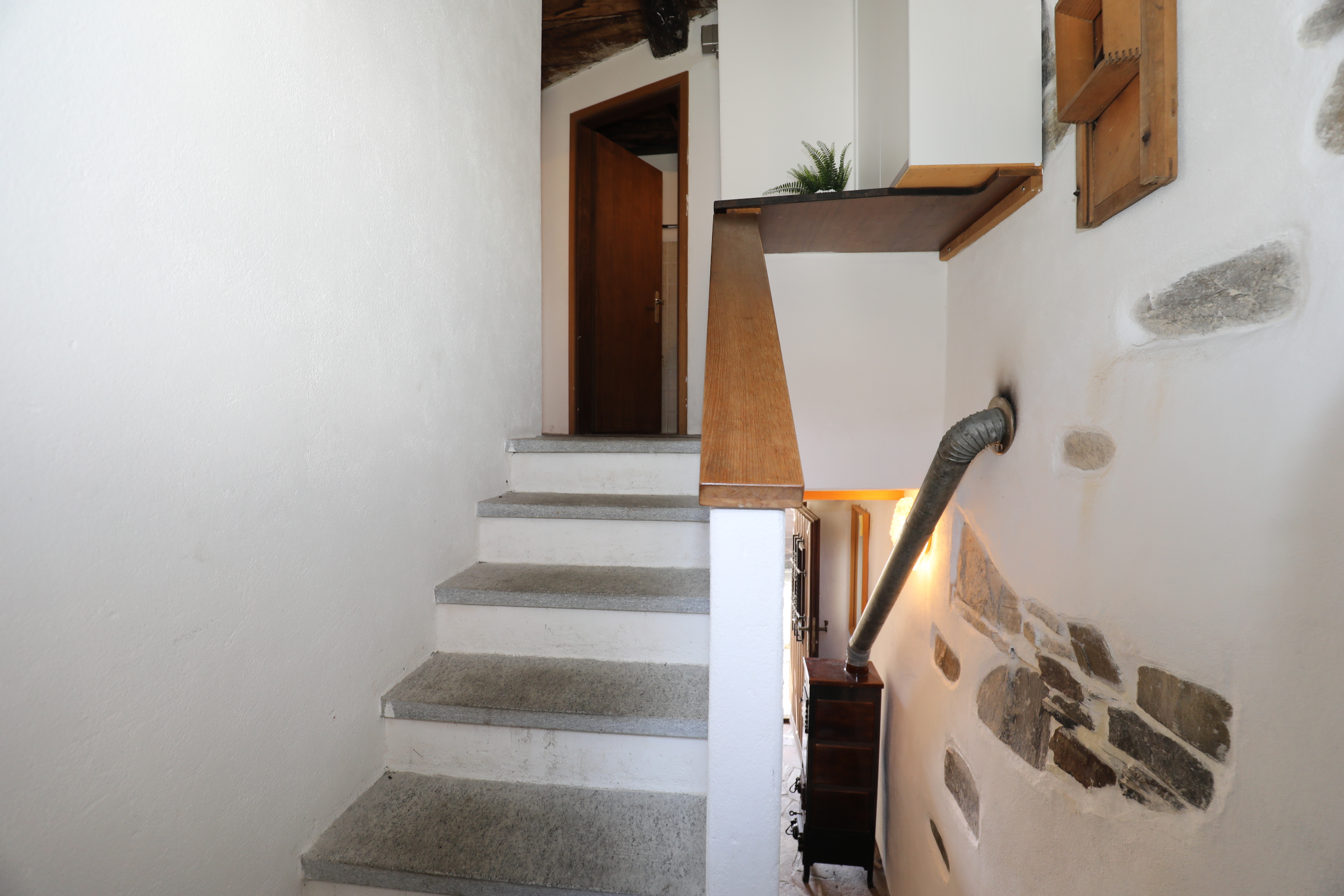 Treppenhaus mit Steintreppe und Holzgeländer