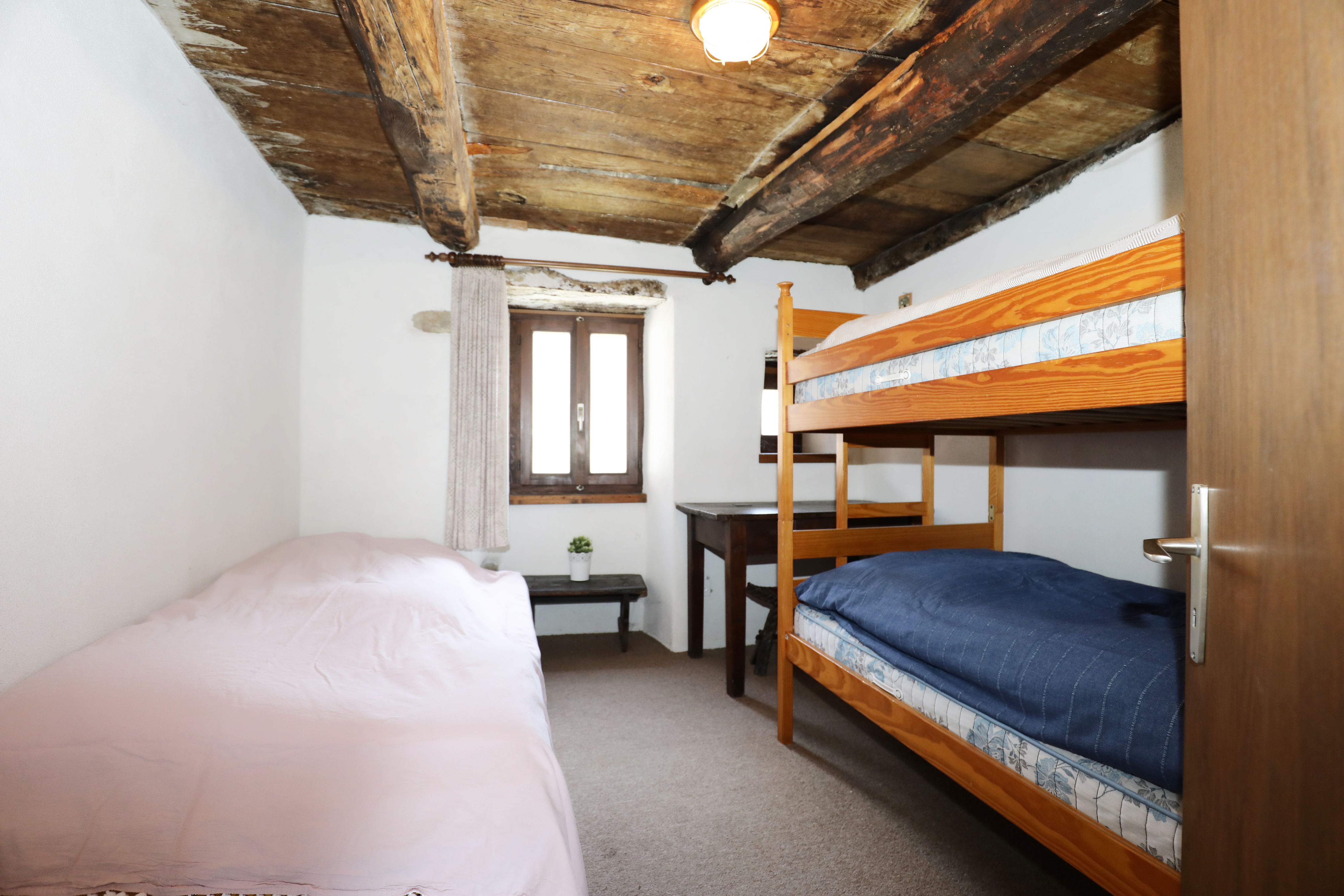 Schlafzimmer mit rustikaler Holzdecke und Etagenbett