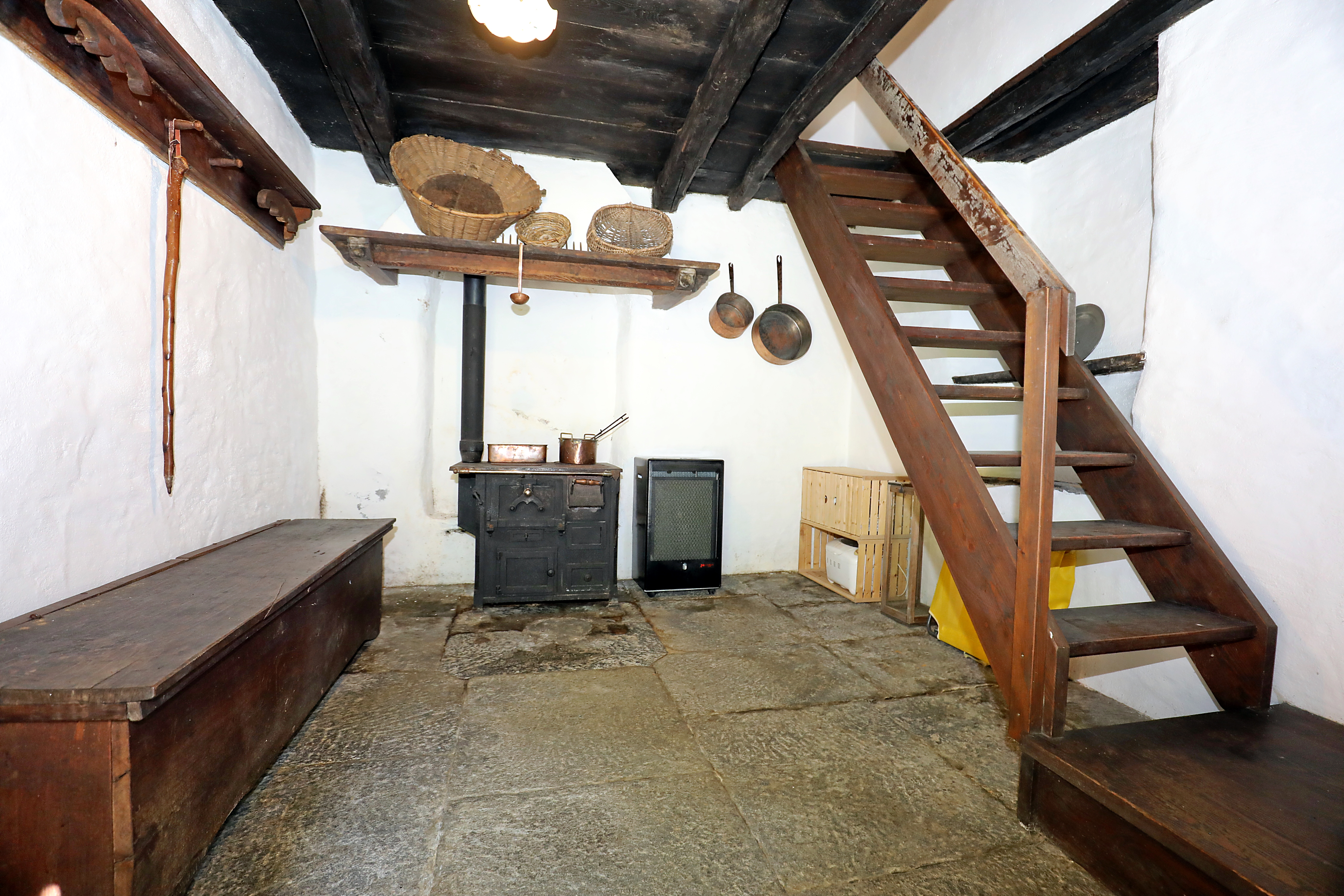 Rustikaler Raum mit Treppe und Kaminofen