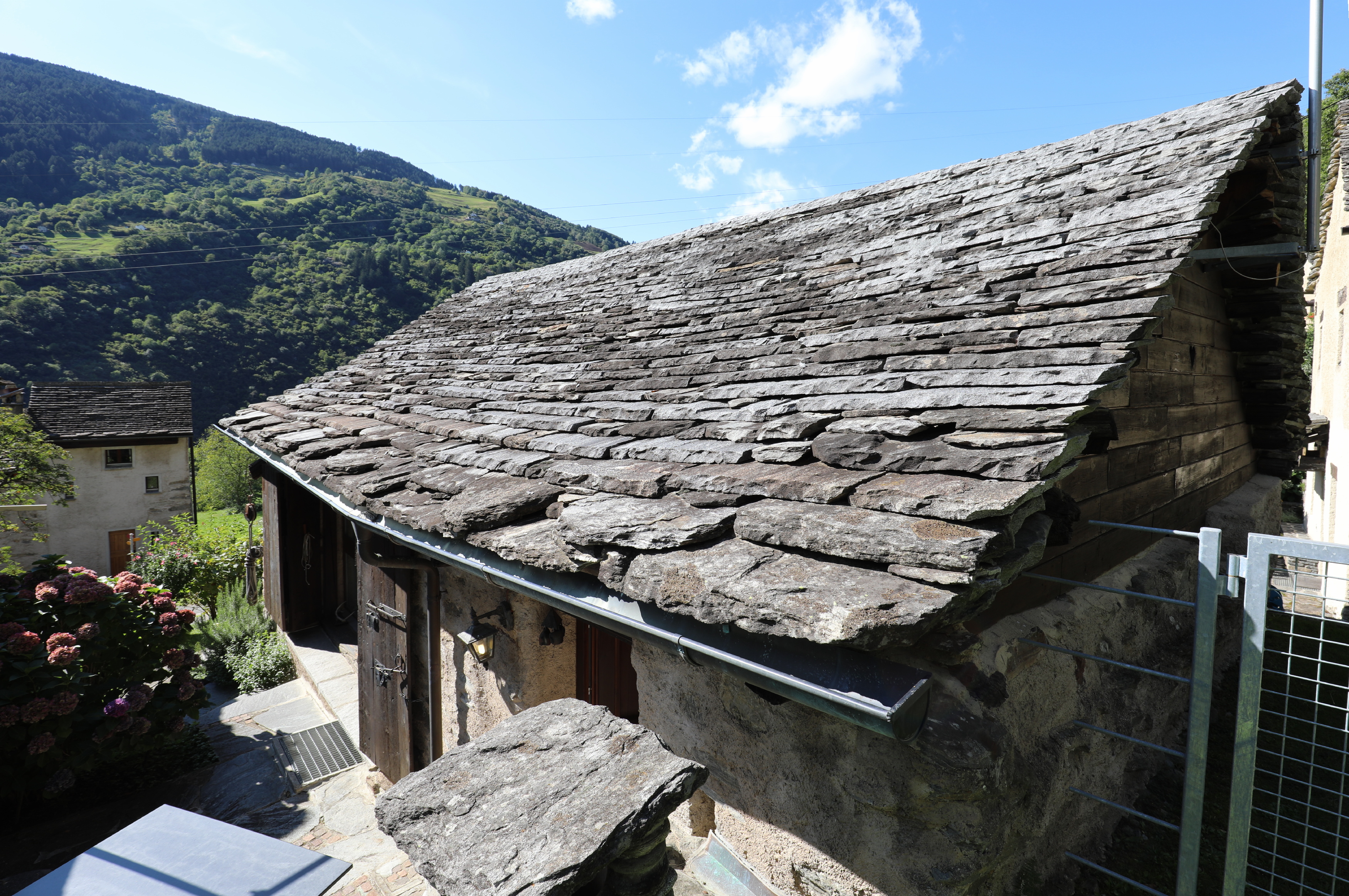 Altes Steinhaus mit Schieferdach und Bergkulisse