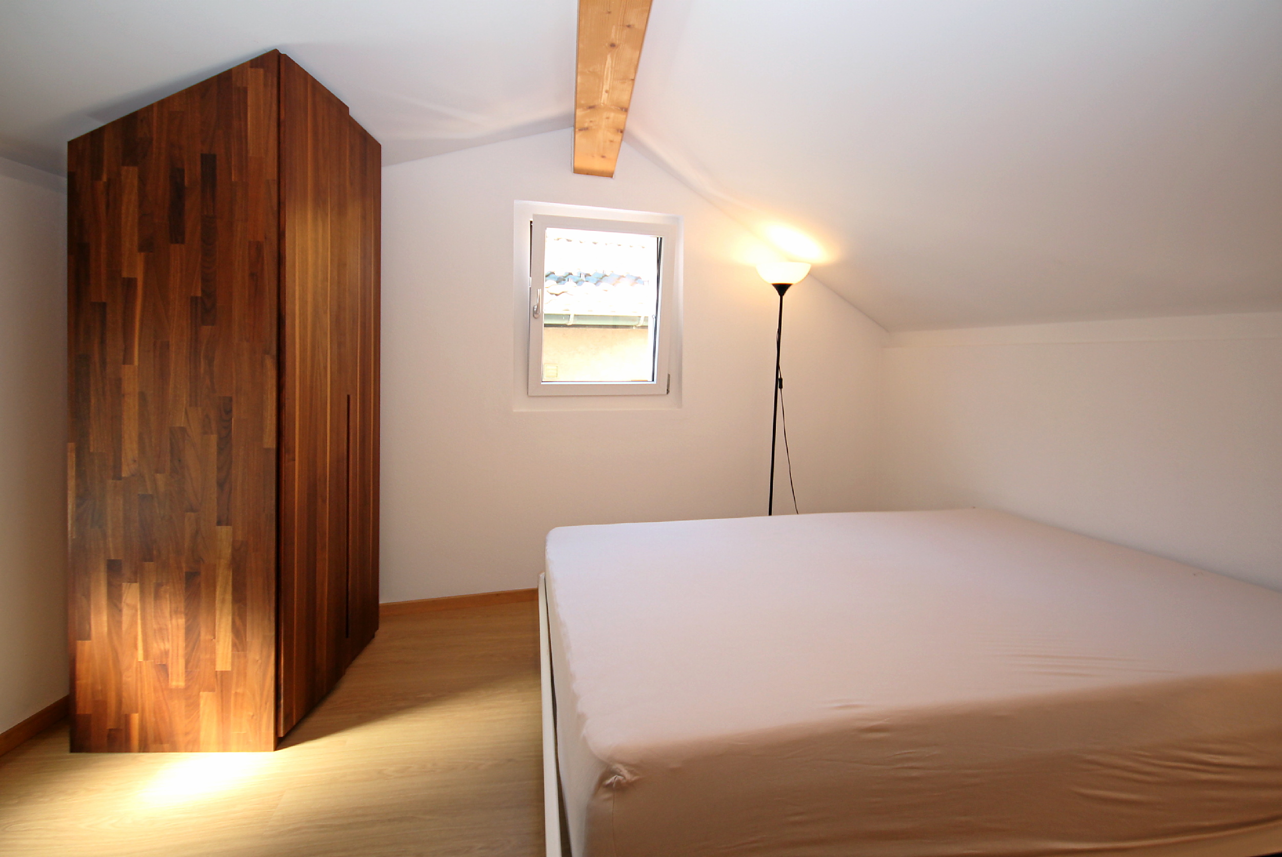 Dachgeschoss-Schlafzimmer mit Bett und Holzschrank