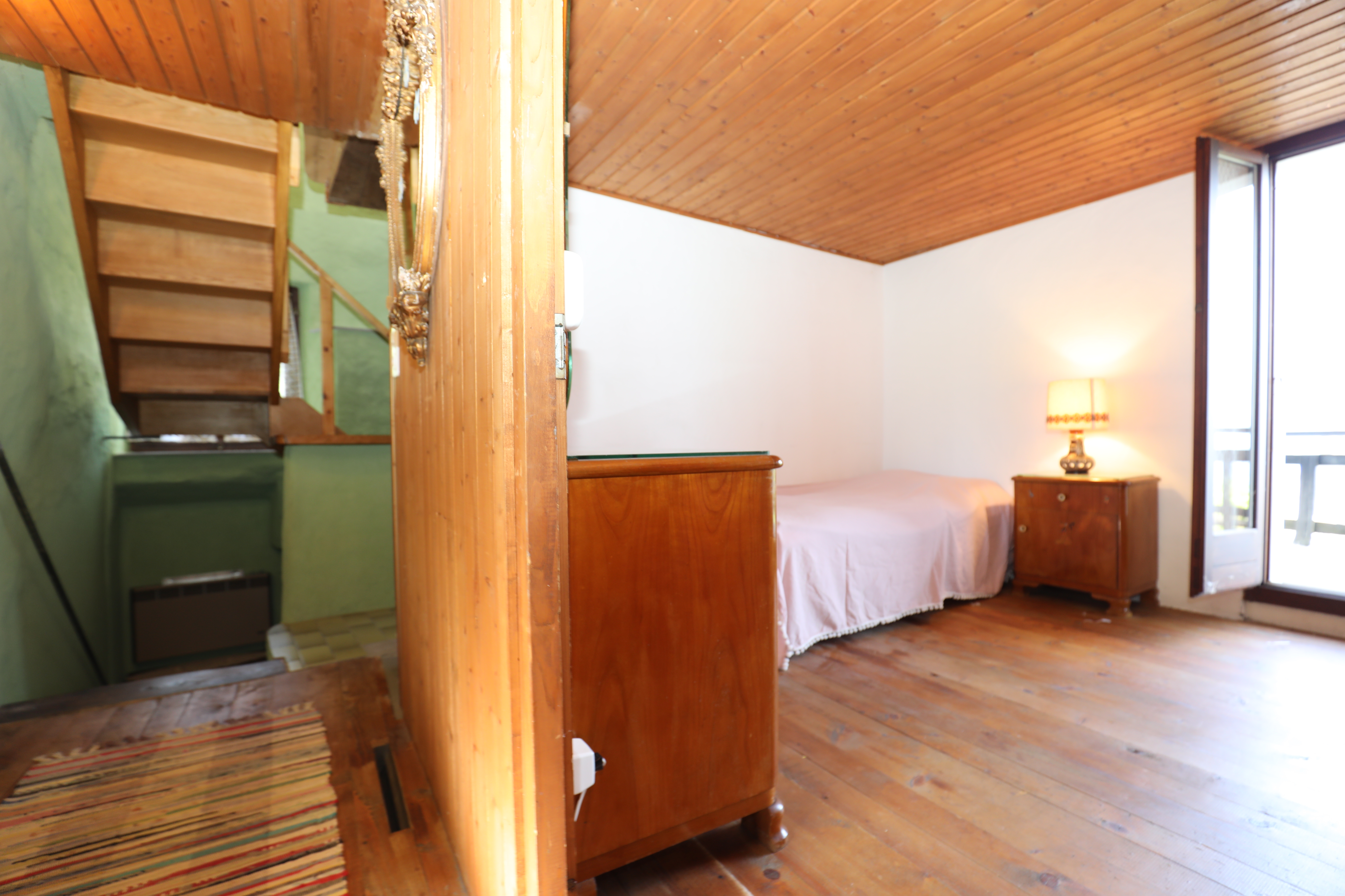 Schlafzimmer mit Holzdecke und Balkonblick