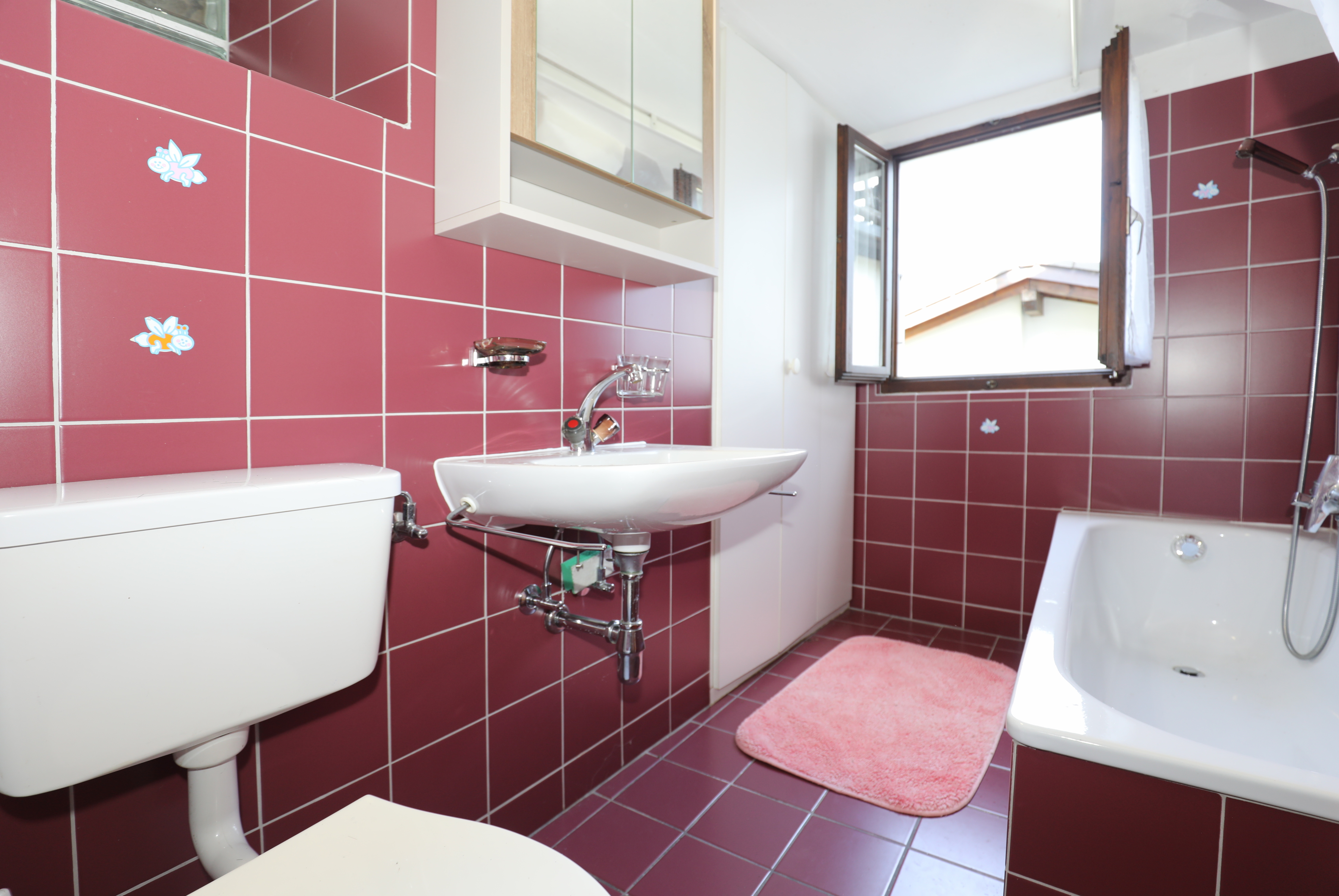 Badezimmer mit rosafarbenen Fliesen und Wanne