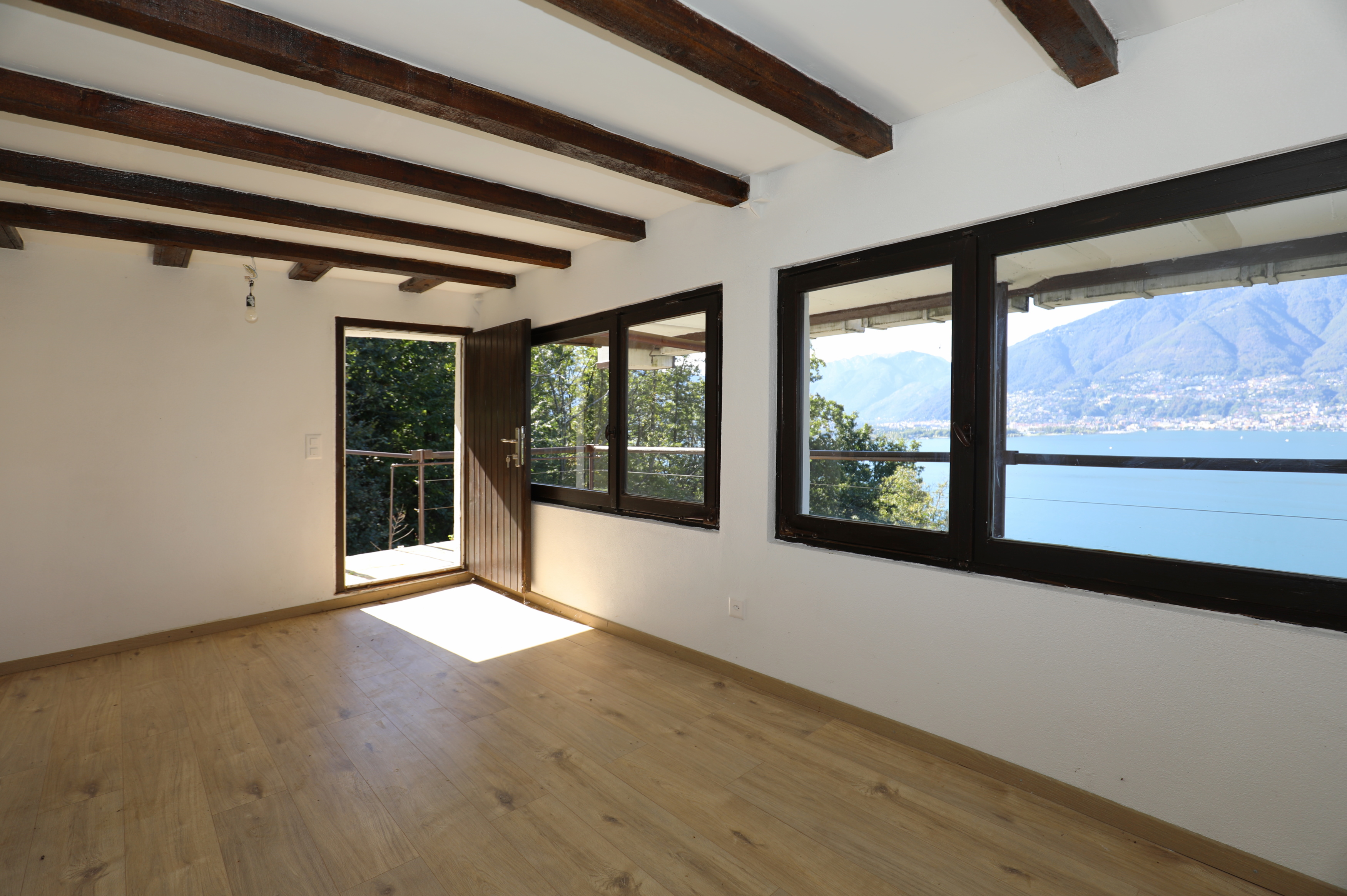 Heller Raum mit Seeblick und Holzbalkendecke
