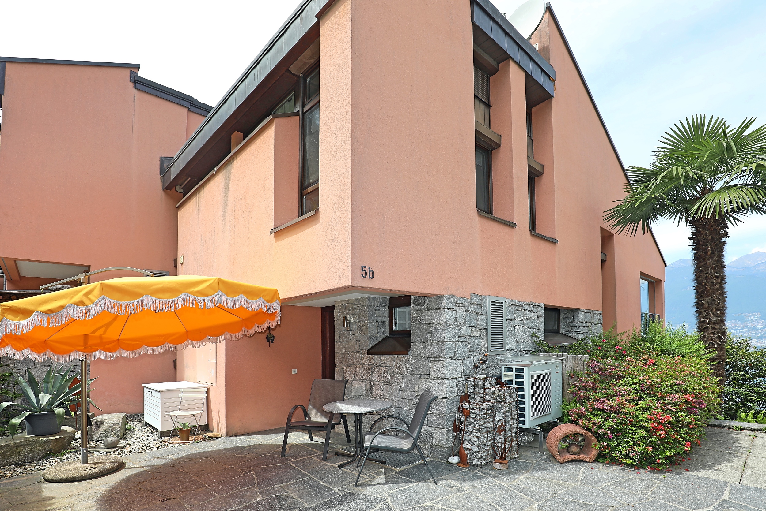 Außenansicht eines terrakottafarbenen Wohnhauses mit Terrasse