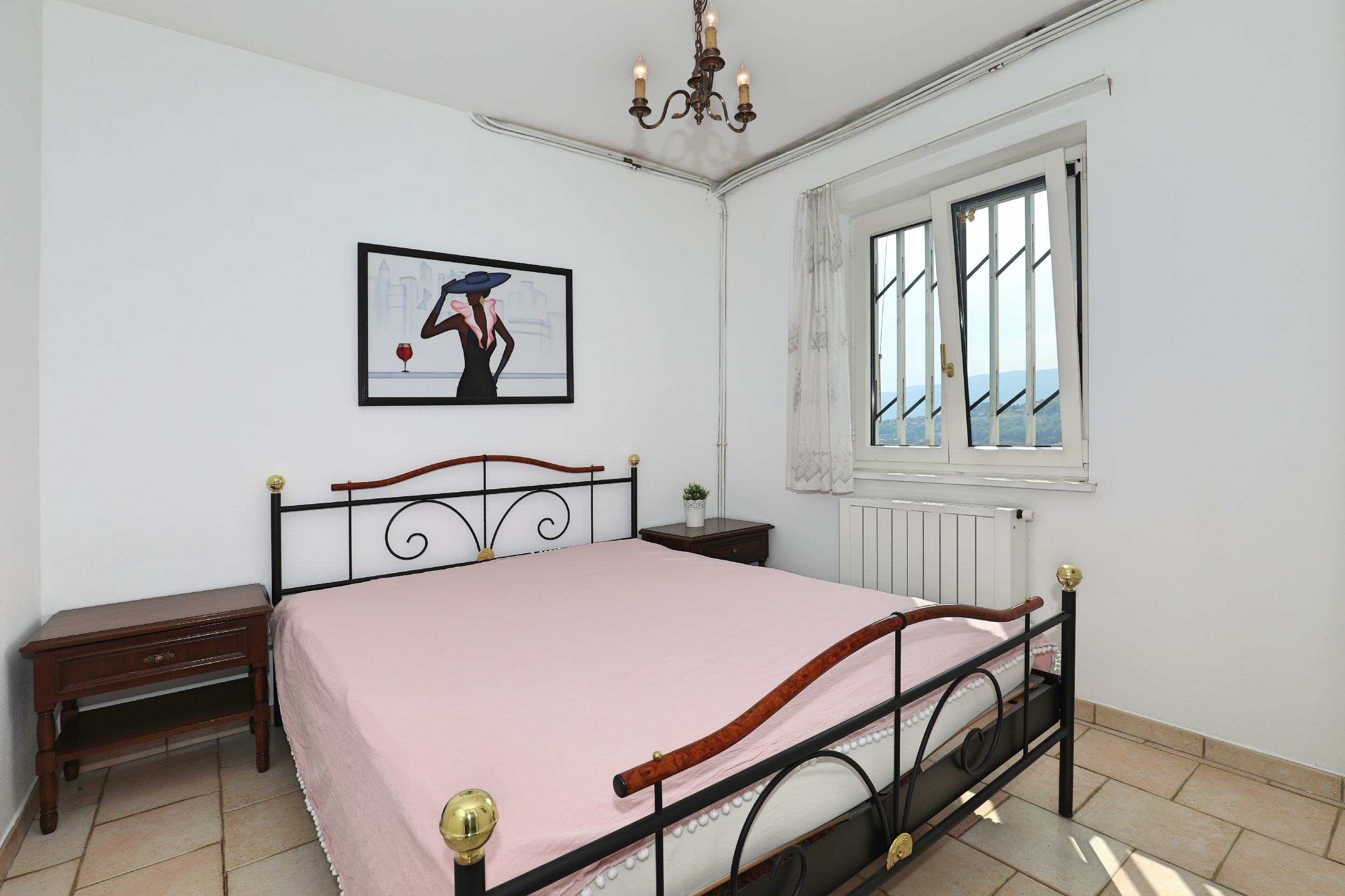 Schlichtes Schlafzimmer mit Eisenbett und Blick ins Grüne
