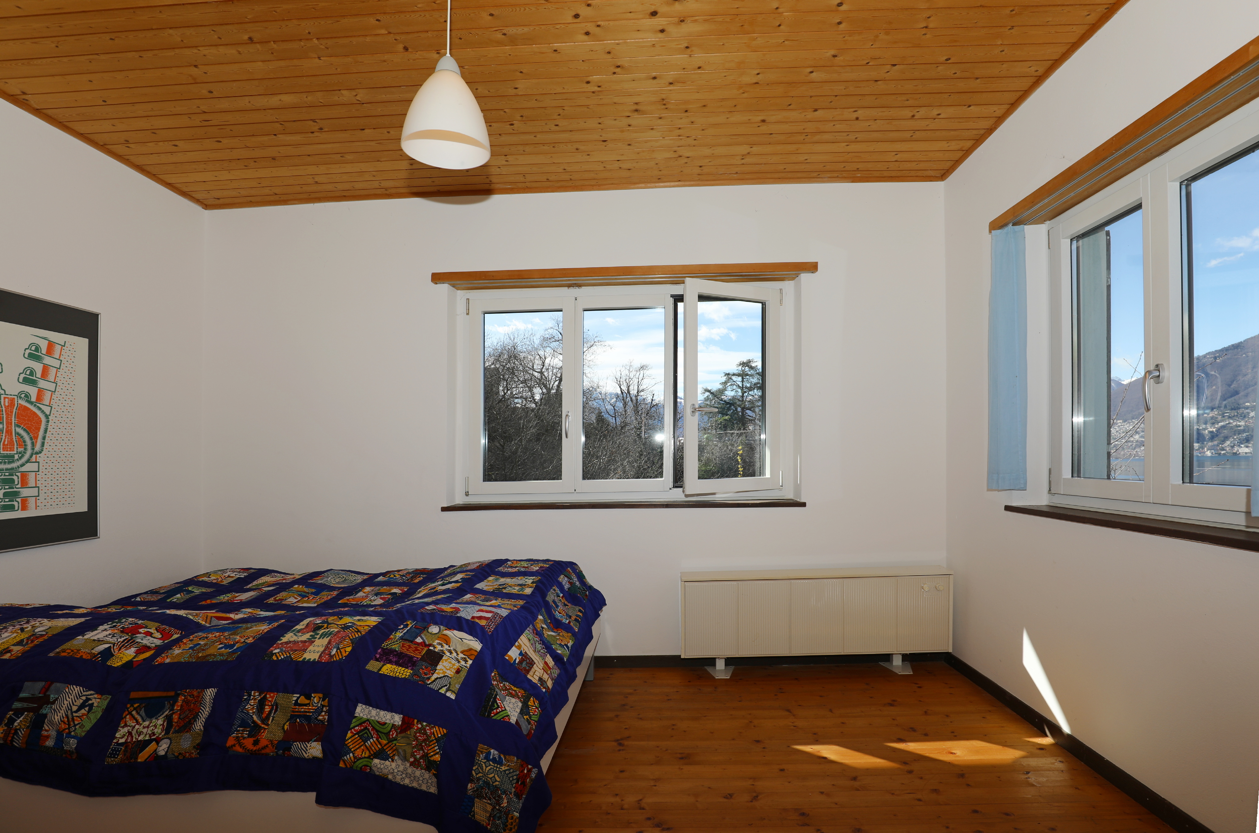 Helles Schlafzimmer mit Holzdecke und Bergblick