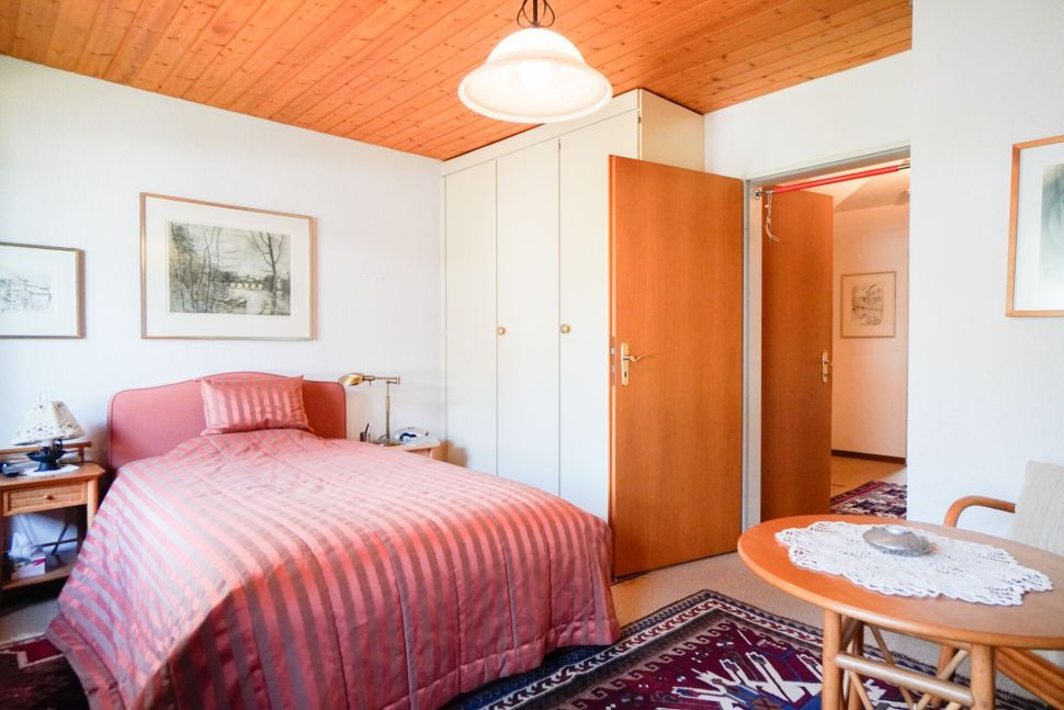 Schlafzimmer mit Holzdecke und rosafarbenem Bett