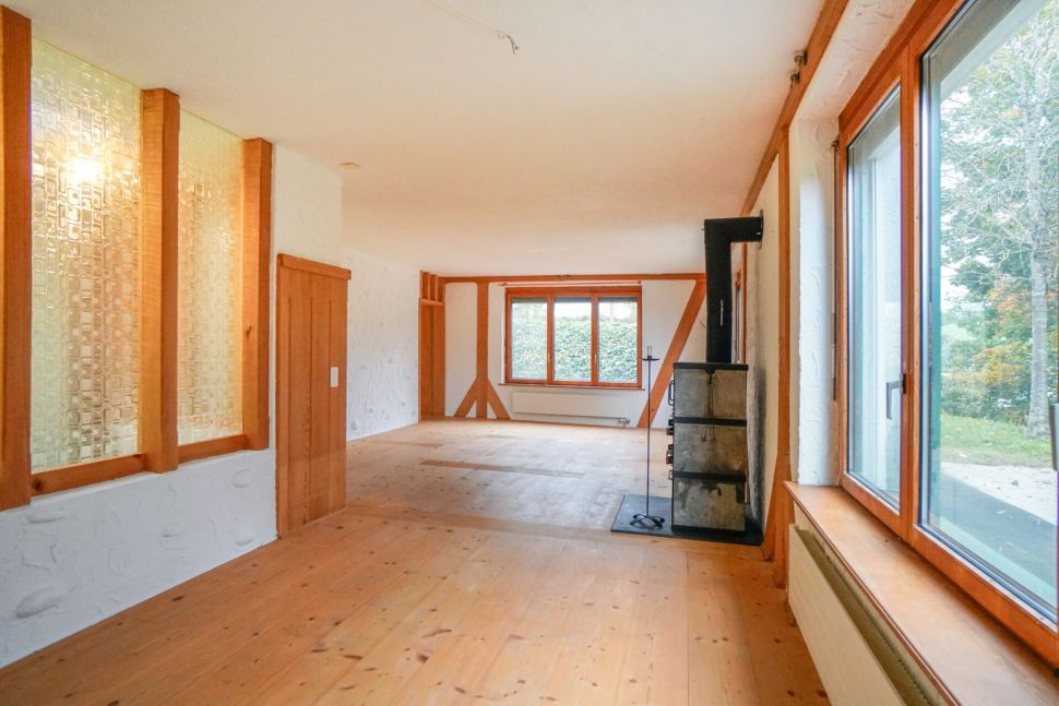 Heller Wohnraum mit Holzfenstern und Kaminofen