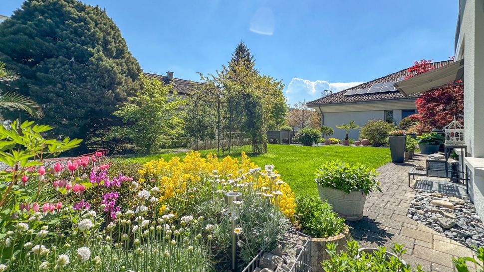 Blühender Garten mit Terrasse und Hausansicht