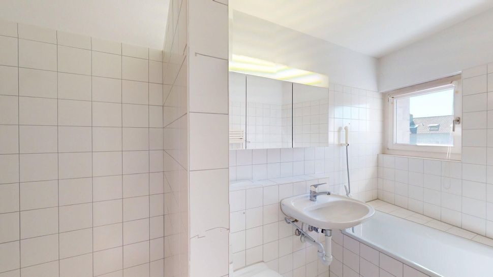 Hell gefliestes Badezimmer mit Badewanne und Waschbecken