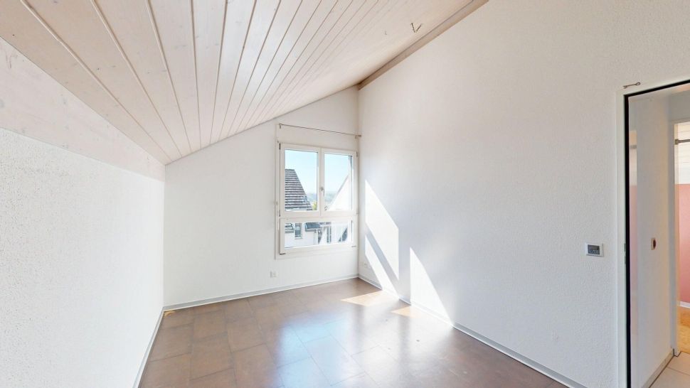Heller leerer Raum mit Dachschräge und kleinem Fenster