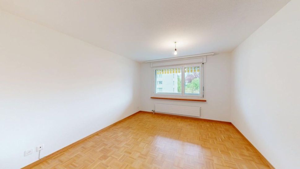 Heller leerer Raum mit Parkettboden und Fenster