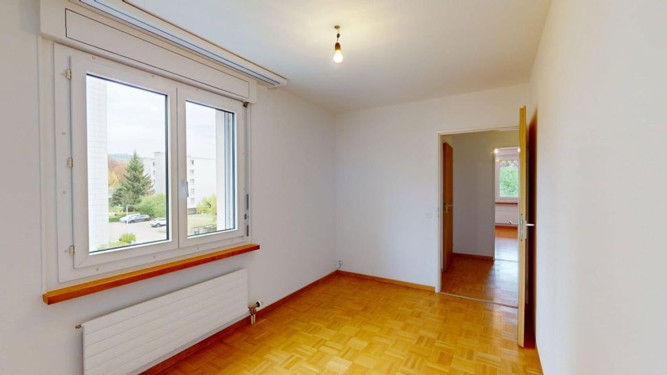 Helles, leeres Zimmer mit Parkett und Fenster
